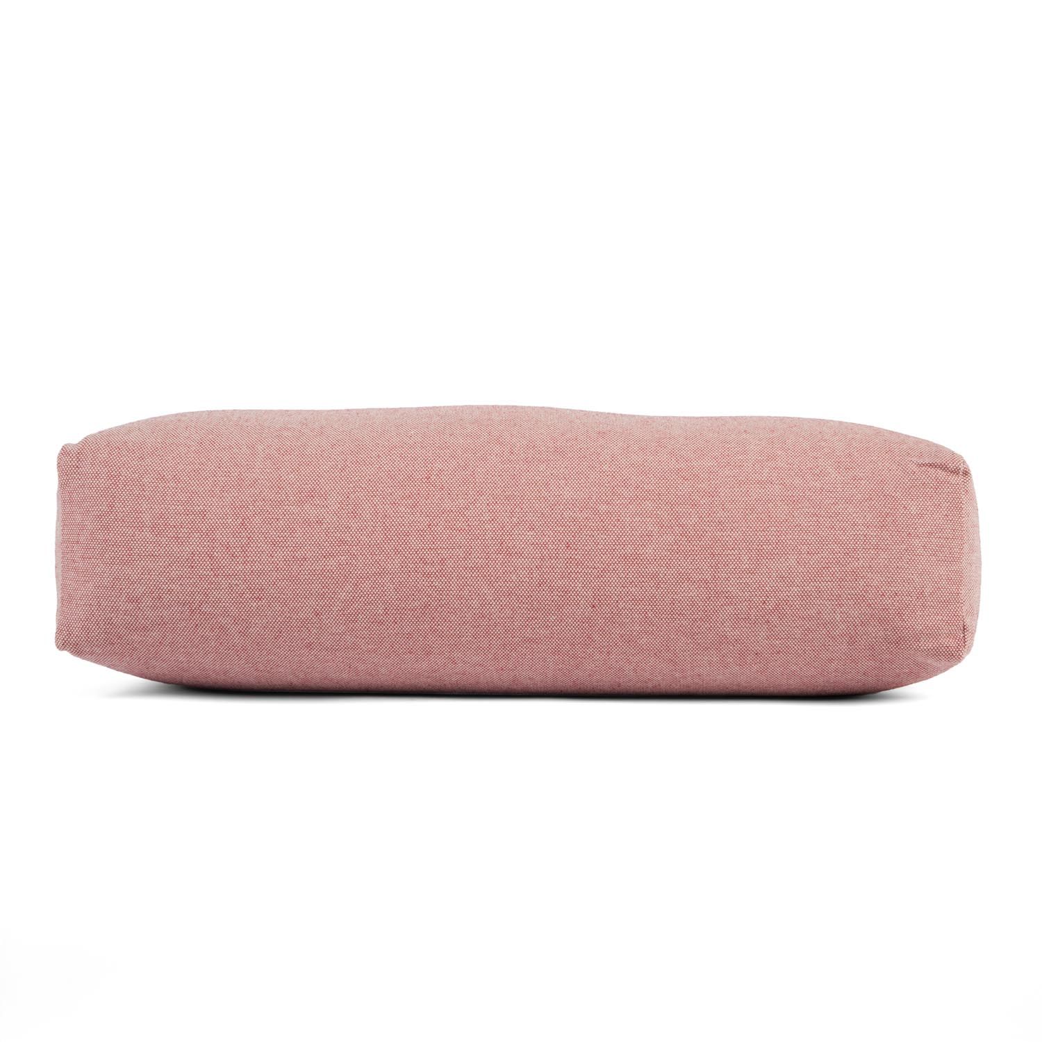 Ein rosafarbener Yoga-Bolster, von der Seite liegend gezeigt, mit glatter Oberfläche und Nähten.