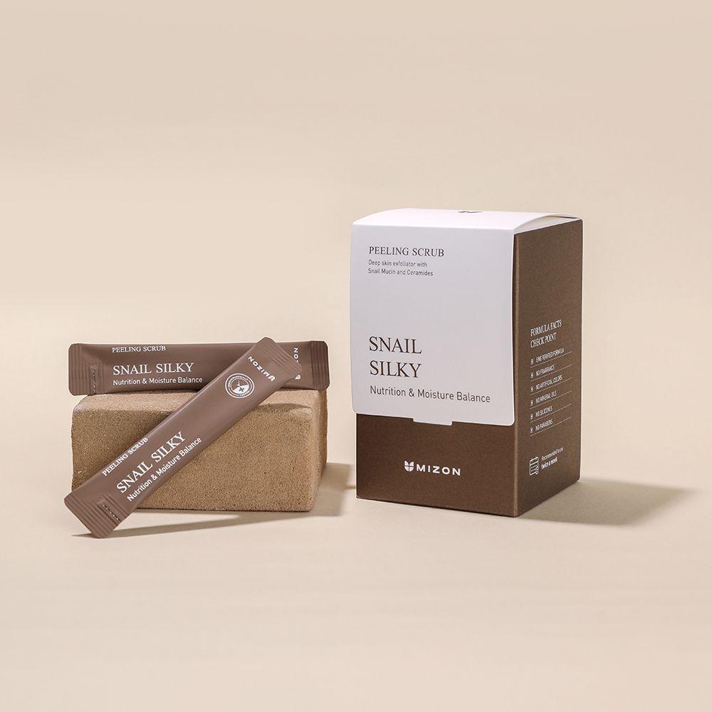 Braune Verpackung mit Produktbeuteln und Karton. Aufschrift: Snail Silky, MIZON. Produktbeutel liegen auf einem Block.
