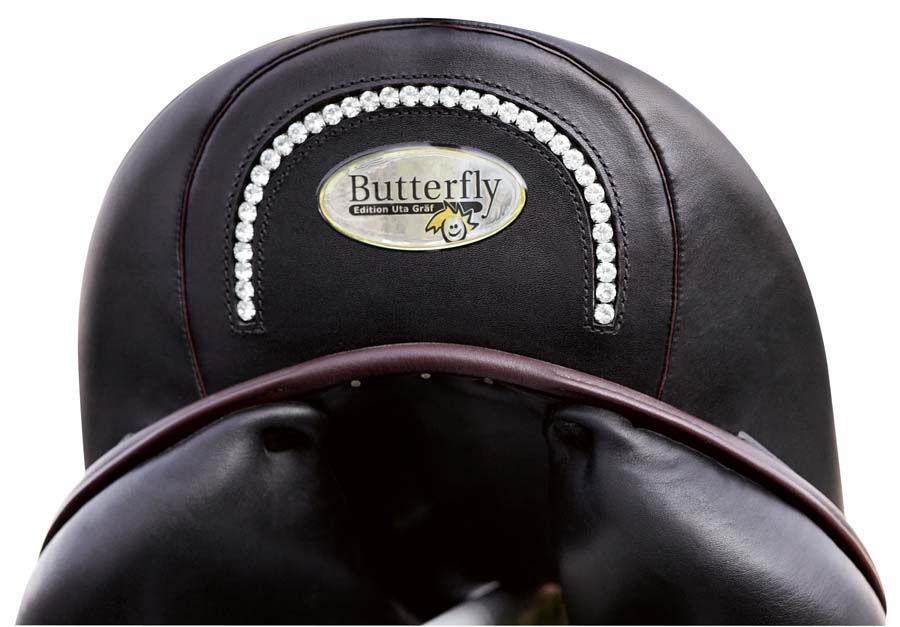 Dressursattel, Nahaufnahme. Schwarzes Leder mit Strasssteinen und Logo. Sattelblatt und Sitzfläche sichtbar.