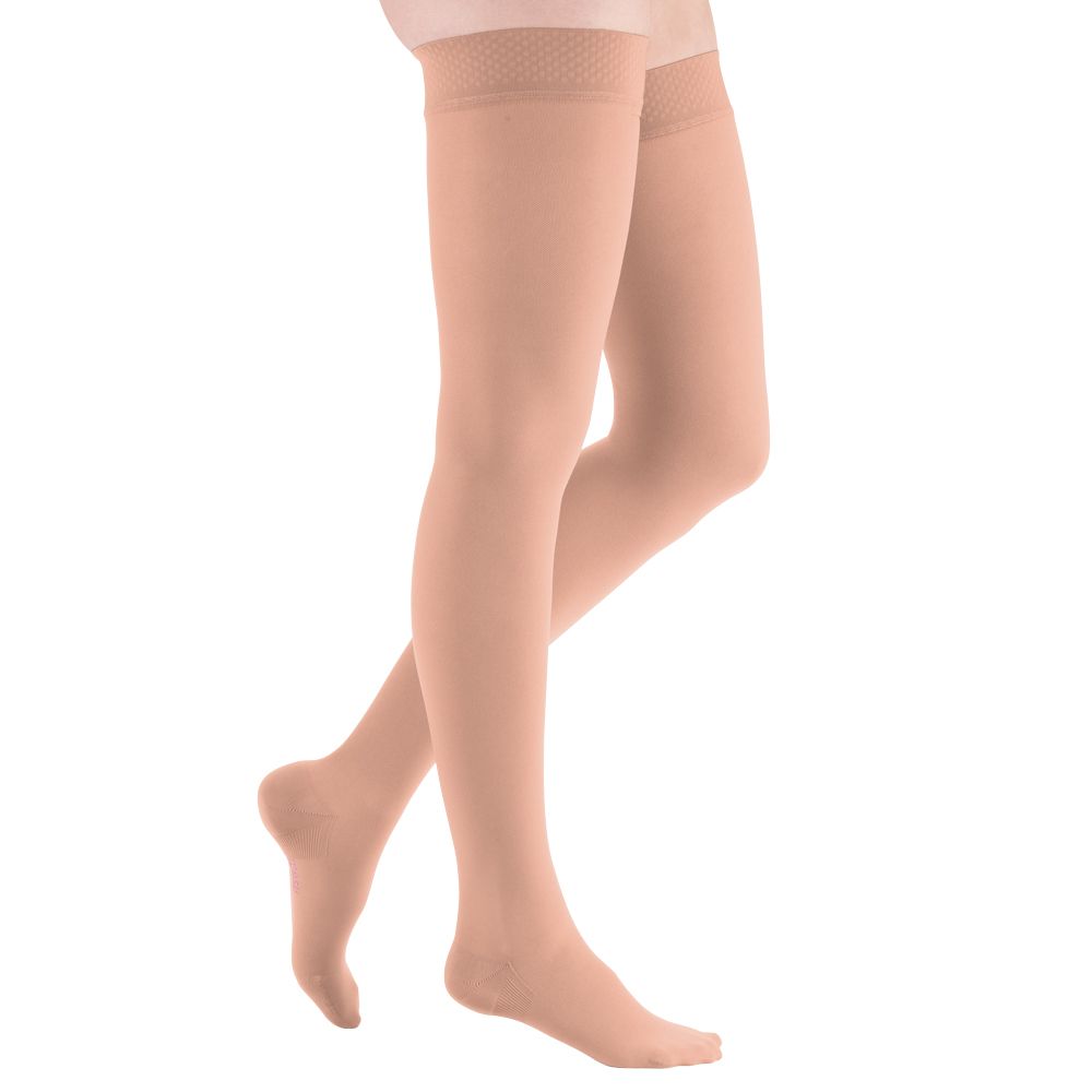 Beine, die hautfarbene Kompressionsstrümpfe tragen. Die Strümpfe enden knapp unterhalb des Knies mit einem strukturierten Abschluss.