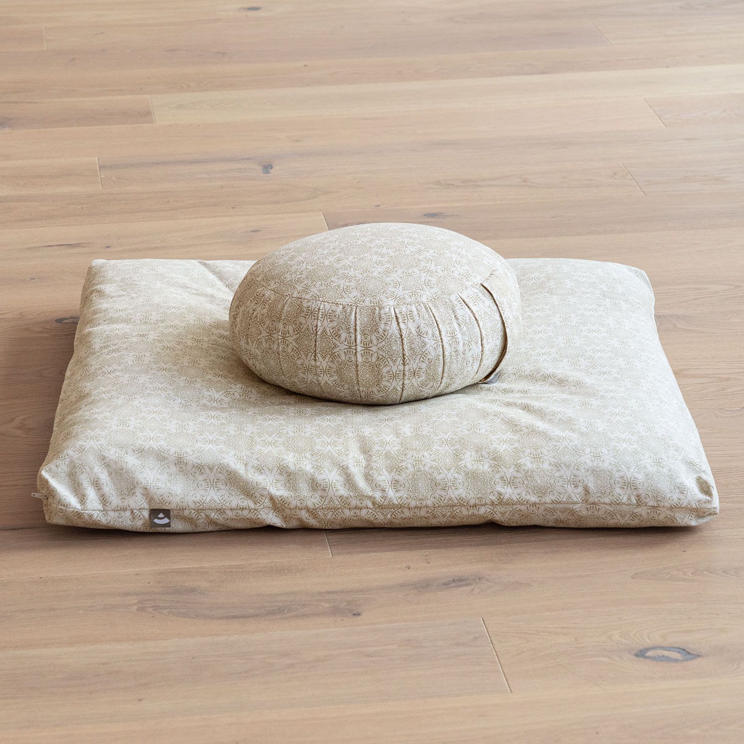 Zafu und Meditationskissen. Beige mit Muster. Rundes Kissen auf rechteckigem Kissen. Auf Holzfußboden.