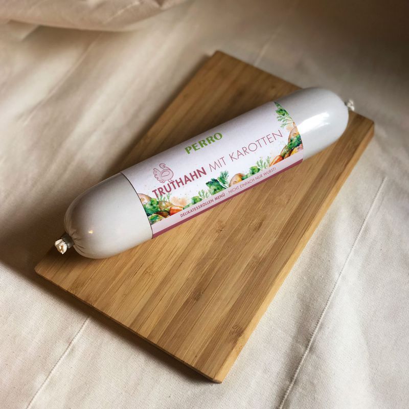 Hundewurst auf Holzbrett. Etikett: PERRO Truthahn mit Karotten. Produkt für Hunde.