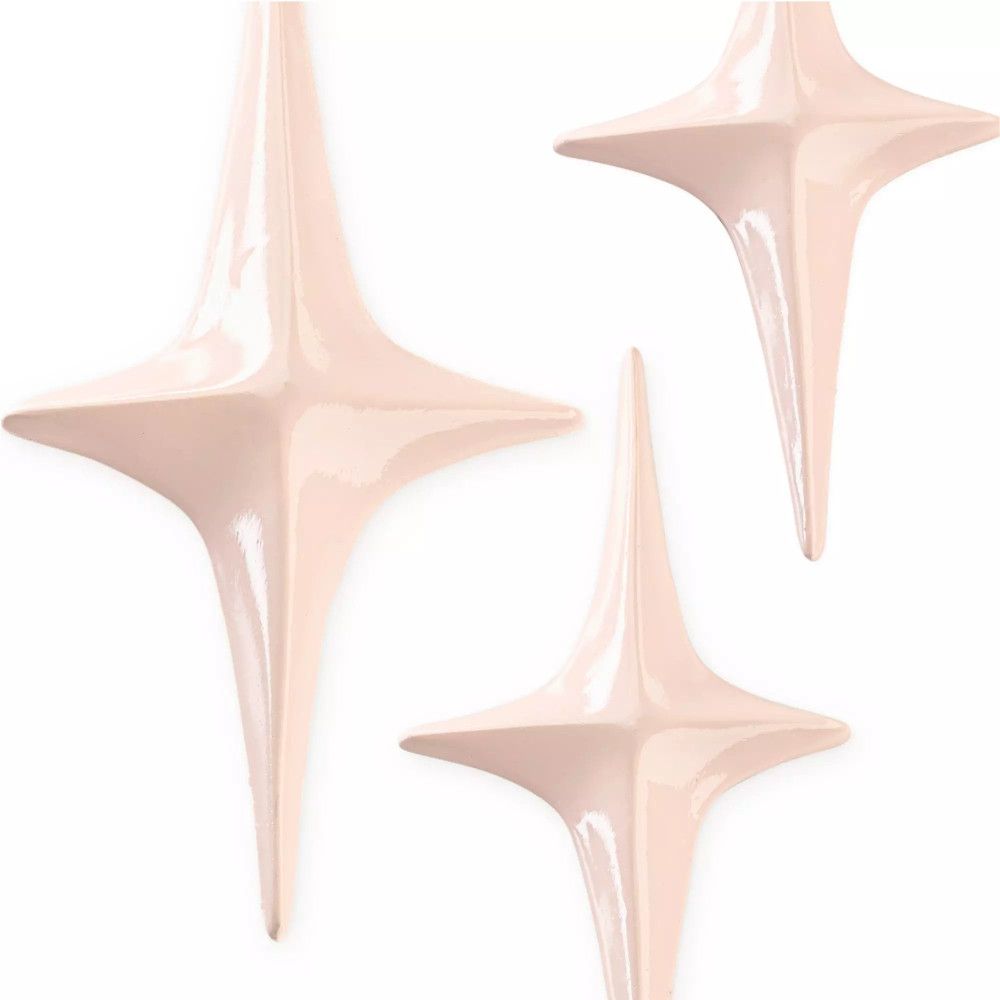 Drei sternförmige Dekorationen in hellem Rosa. Glänzende Oberfläche.