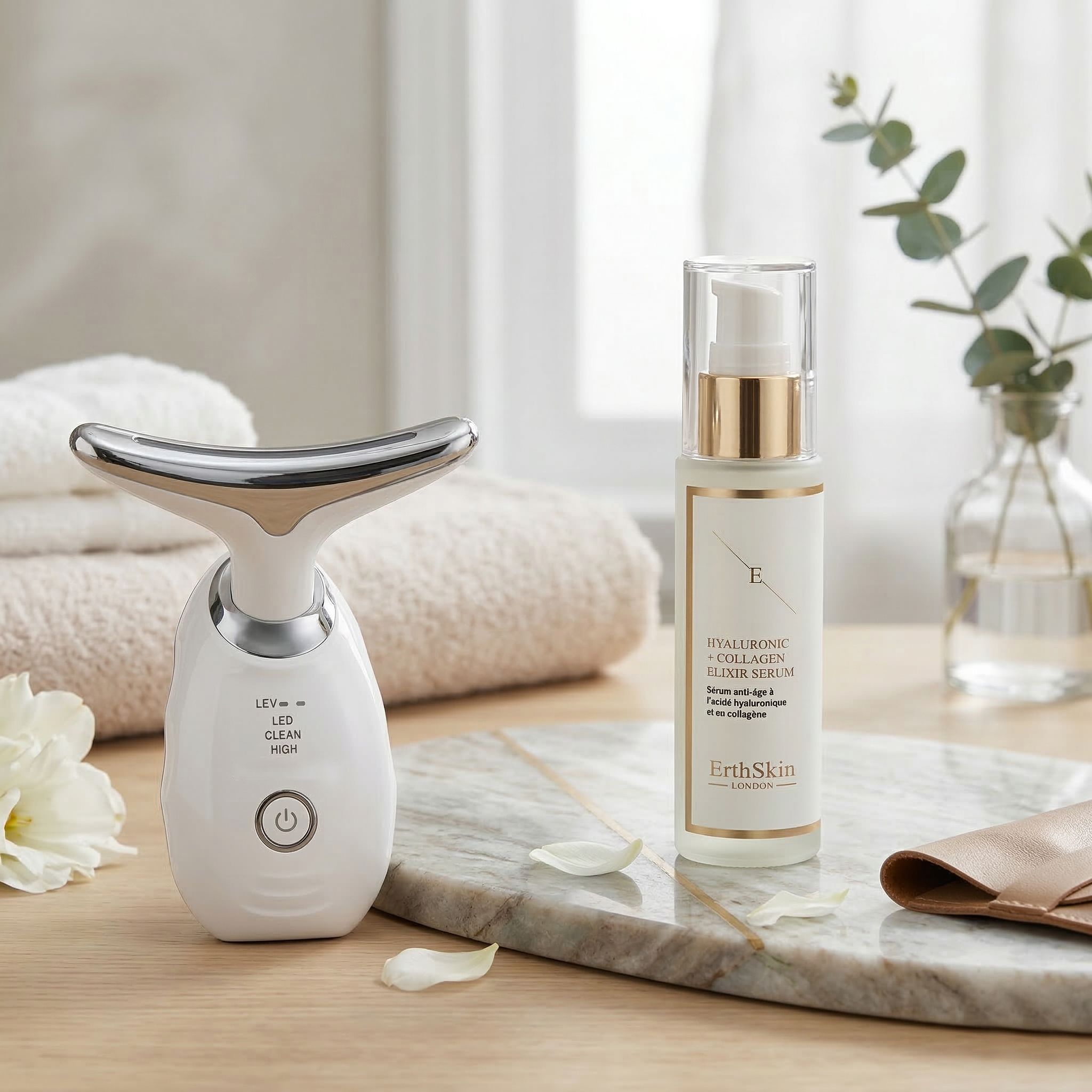 Erth Skin London Hals-LED-Massagegerät und Hyaluronsäure-Kollagen-Elixier-Serum auf Marmorplatte.