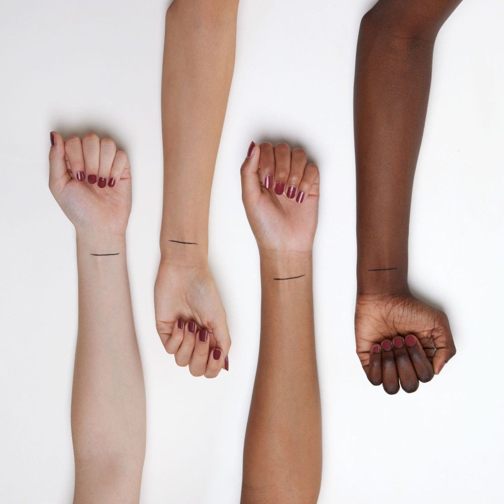 Vier Arme mit unterschiedlichen Hauttönen. Auf jedem Arm ein schwarzer Lidstrich.