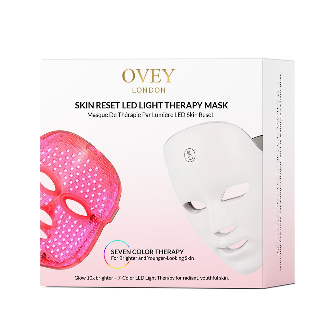 Produktverpackung mit einer weißen LED-Gesichtsmaske. Text: SKIN RESET LED LIGHT THERAPY MASK. Sieben Farben.