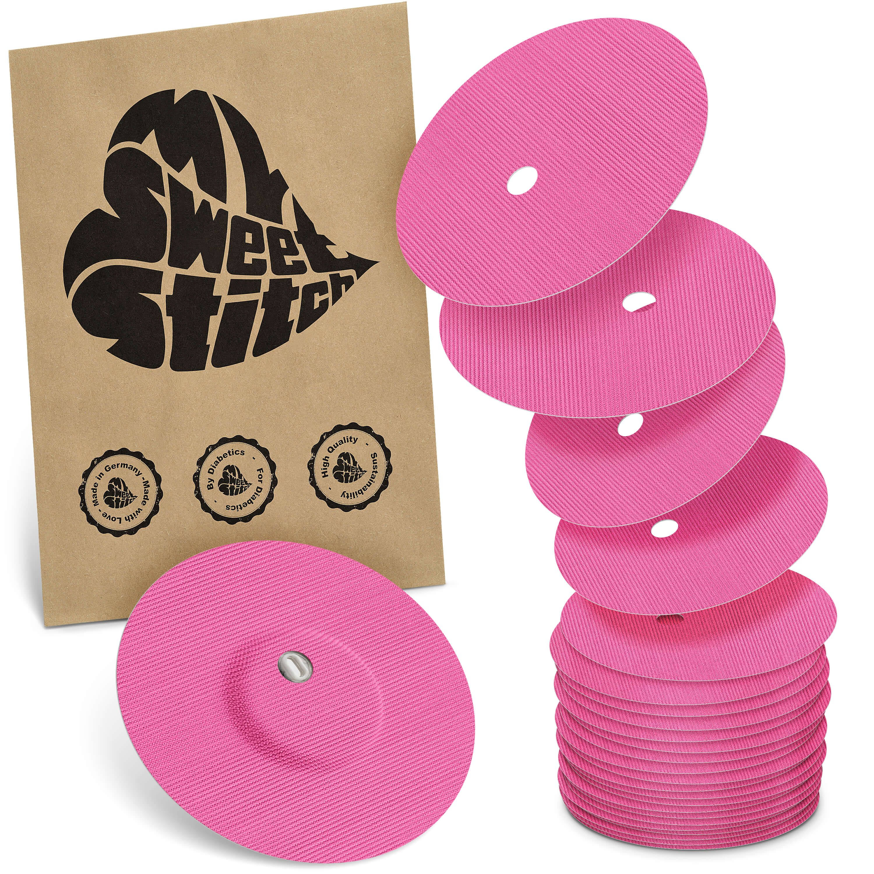 Rosa Fixierpflaster mit Belüftungsloch. Neben einer braunen Verpackung mit Logo liegen mehrere Pflaster gestapelt.