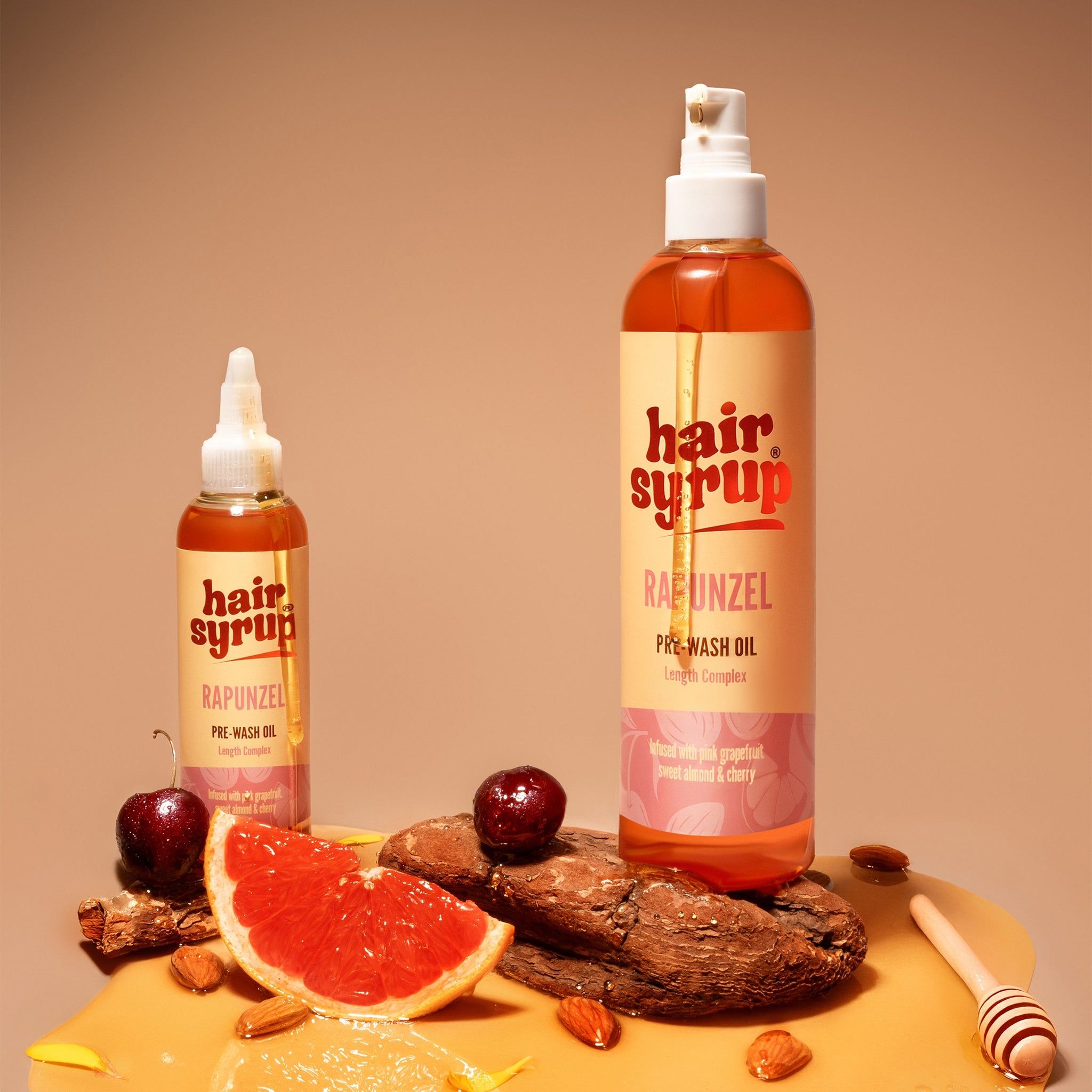 Zwei Hair Syrup Flaschen, eine mit Sprühkopf. Dazu Grapefruit, Honig und Mandeln.