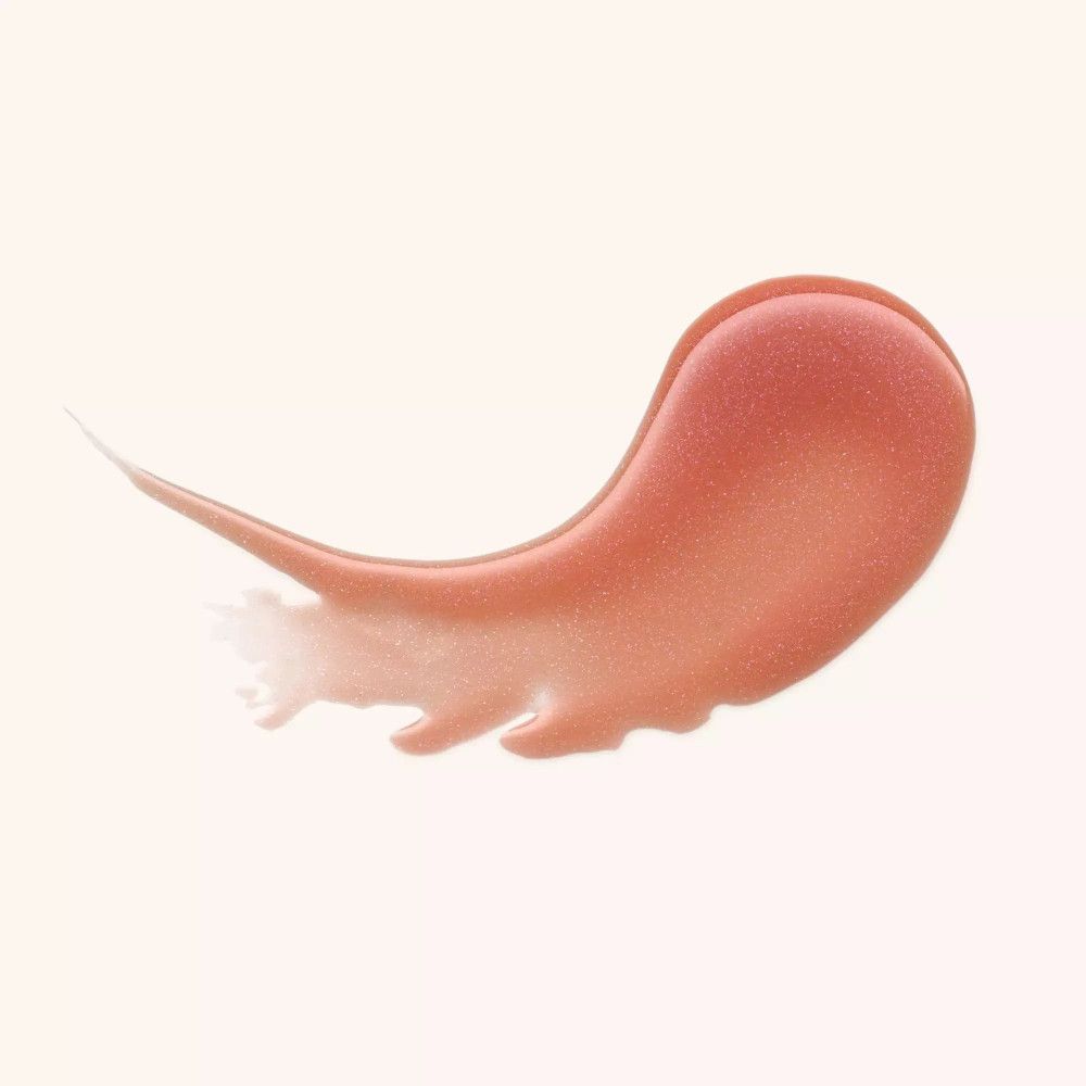 Ausgestrichene, glänzende Lippenbalsam-Probe in rosa-goldener Farbe auf hellem Hintergrund.