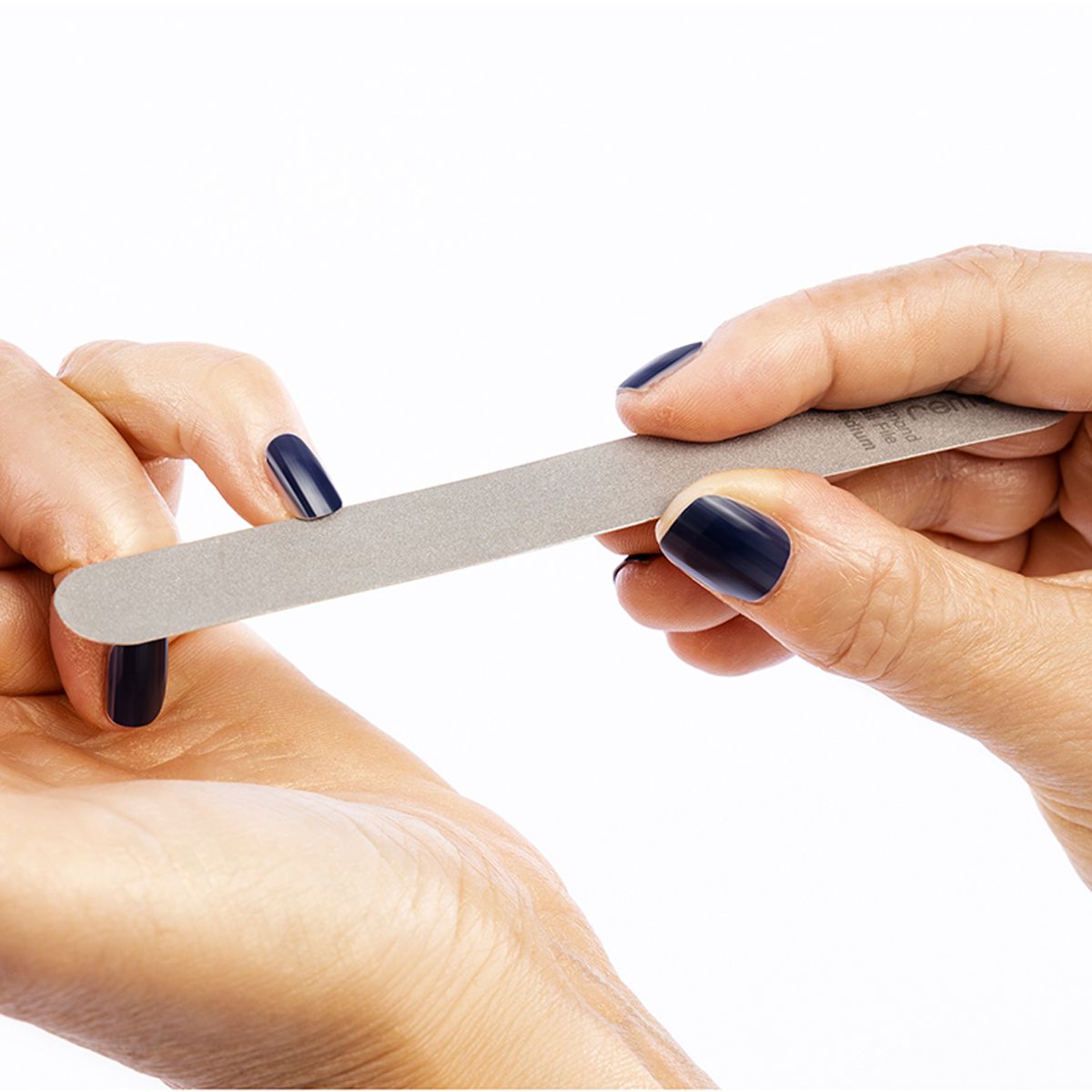 Hände feilen einen Nagel mit einer grauen Feile. Aufschrift: remos Diamond Nail File medium.