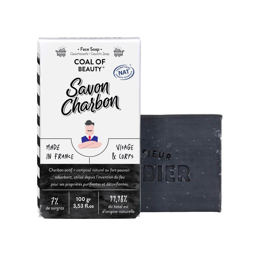 Schwarze Seife und Verpackung. Text: "Savon Charbon", "Visage & Corps". Logo: Monsieur BARBIER.
