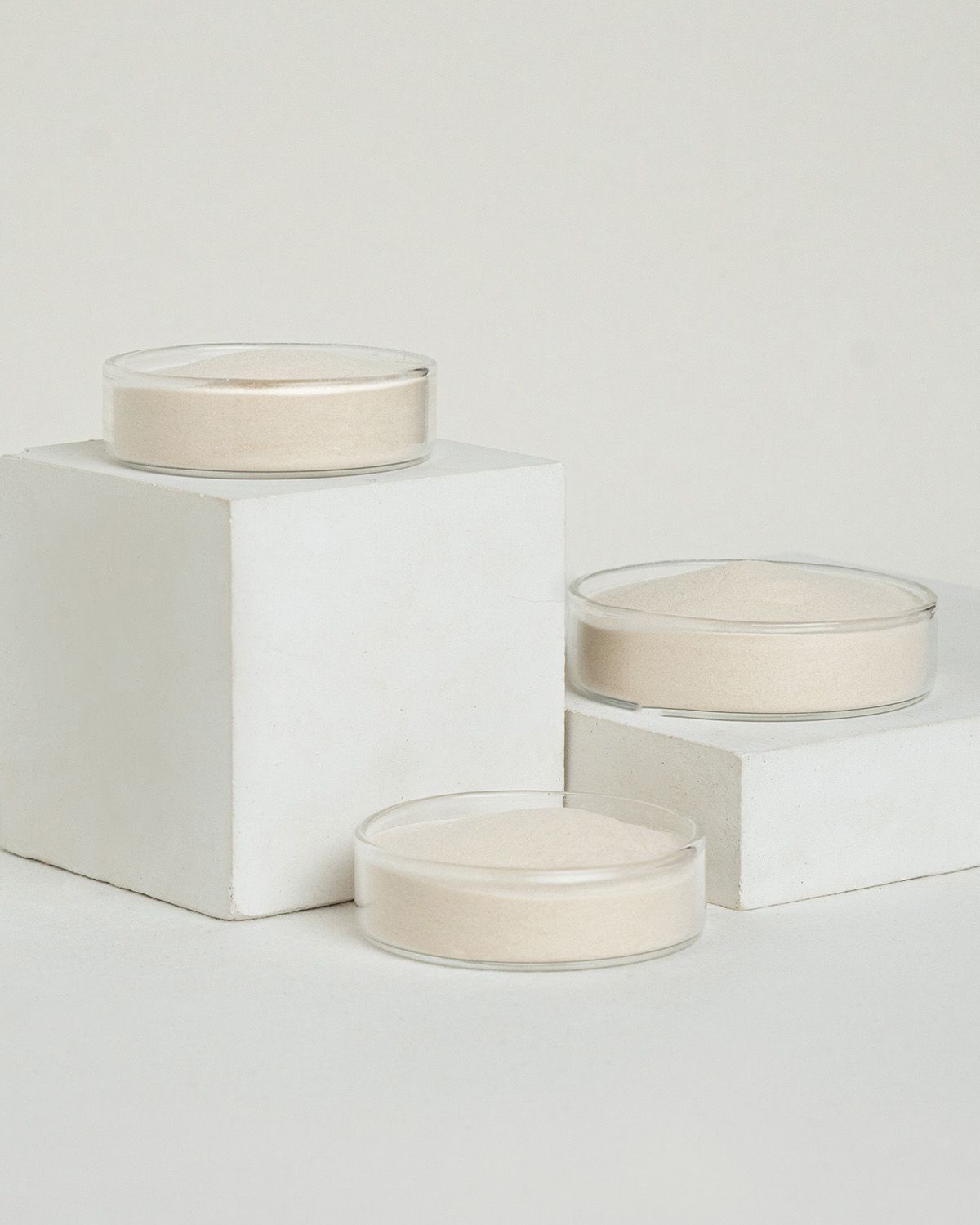 Drei Schalen mit Agar Agar Pulver auf weißen geometrischen Blöcken.