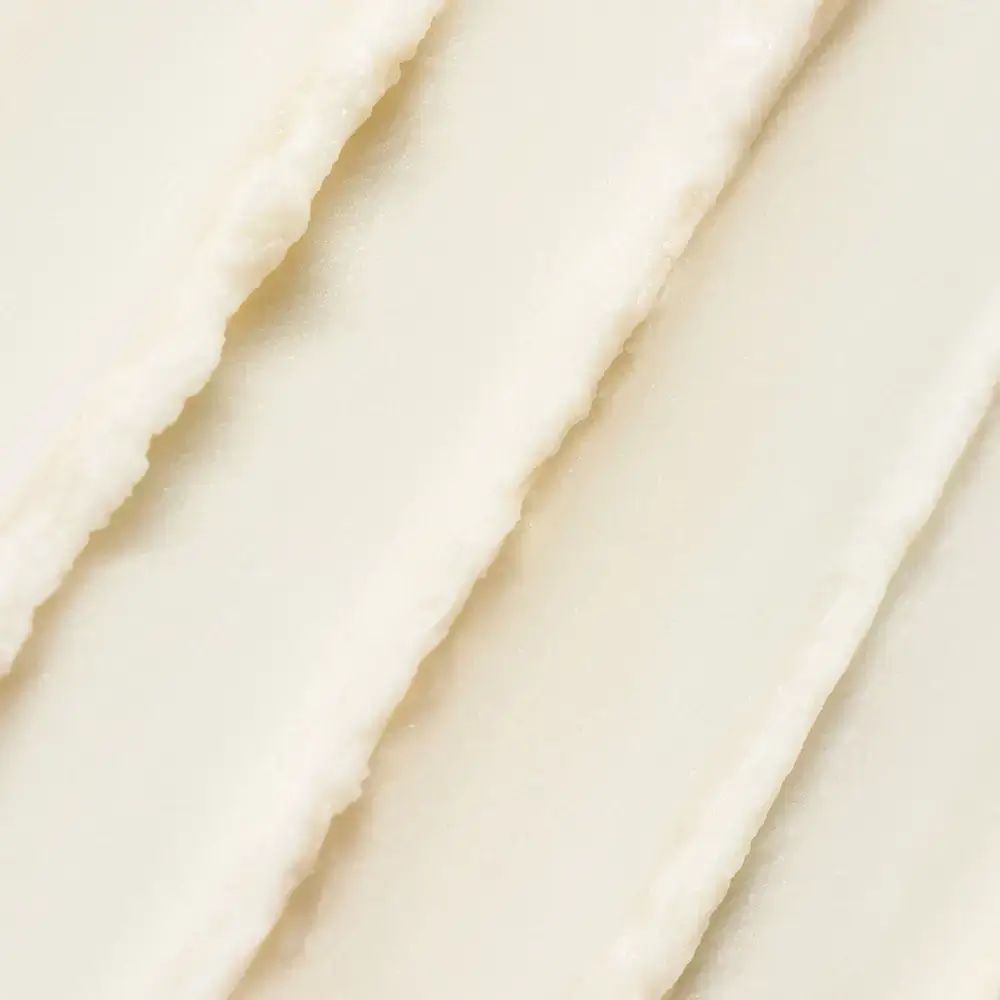 Nahaufnahme von cremiger, weißer Sonnencreme-Textur. Diagonale Streifen. Textur ist uneben.