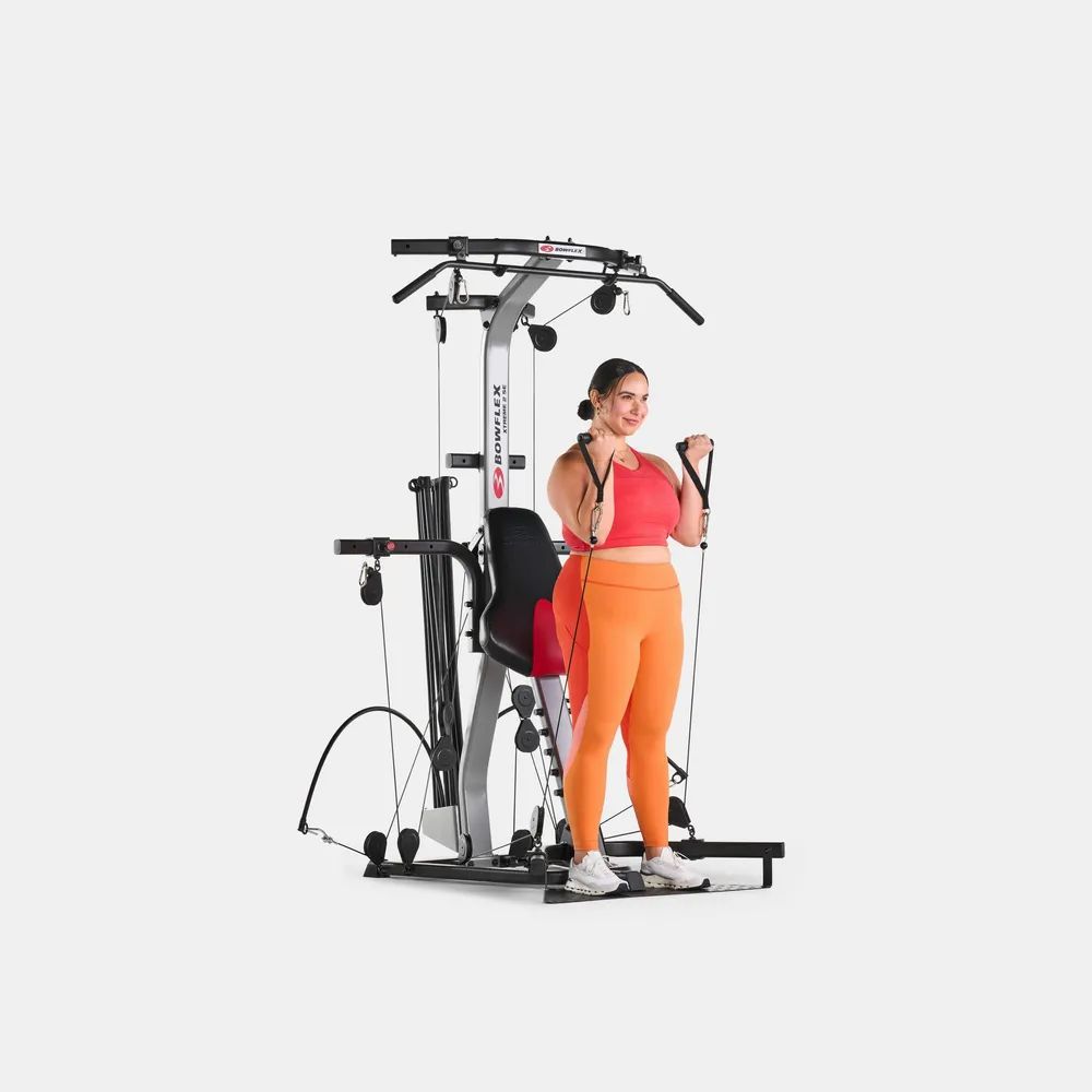 Frau trainiert an einem Fitnessgerät. Graue und schwarze Elemente. Rote und orangefarbene Kleidung.