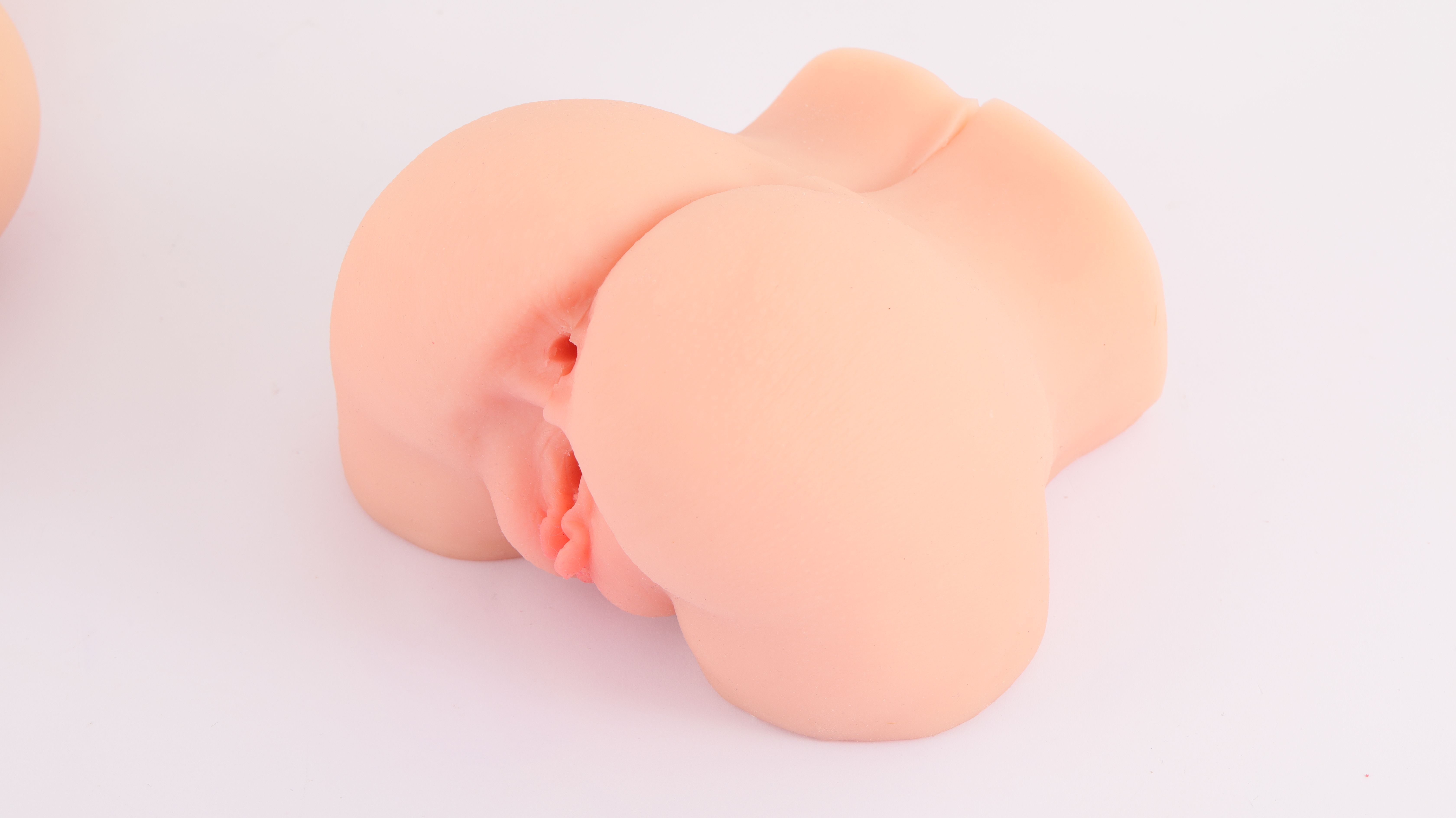 Rosa, anatomisch geformtes Produkt. Weiche, abgerundete Form mit sichtbaren Details. Auf weißem Hintergrund.