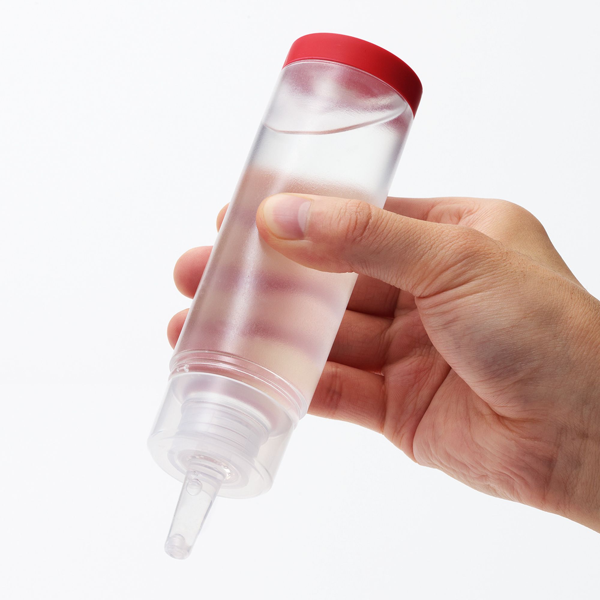 Durchsichtige Flasche mit rotem Deckel, gehalten von einer Hand. Enthält eine klare Flüssigkeit.