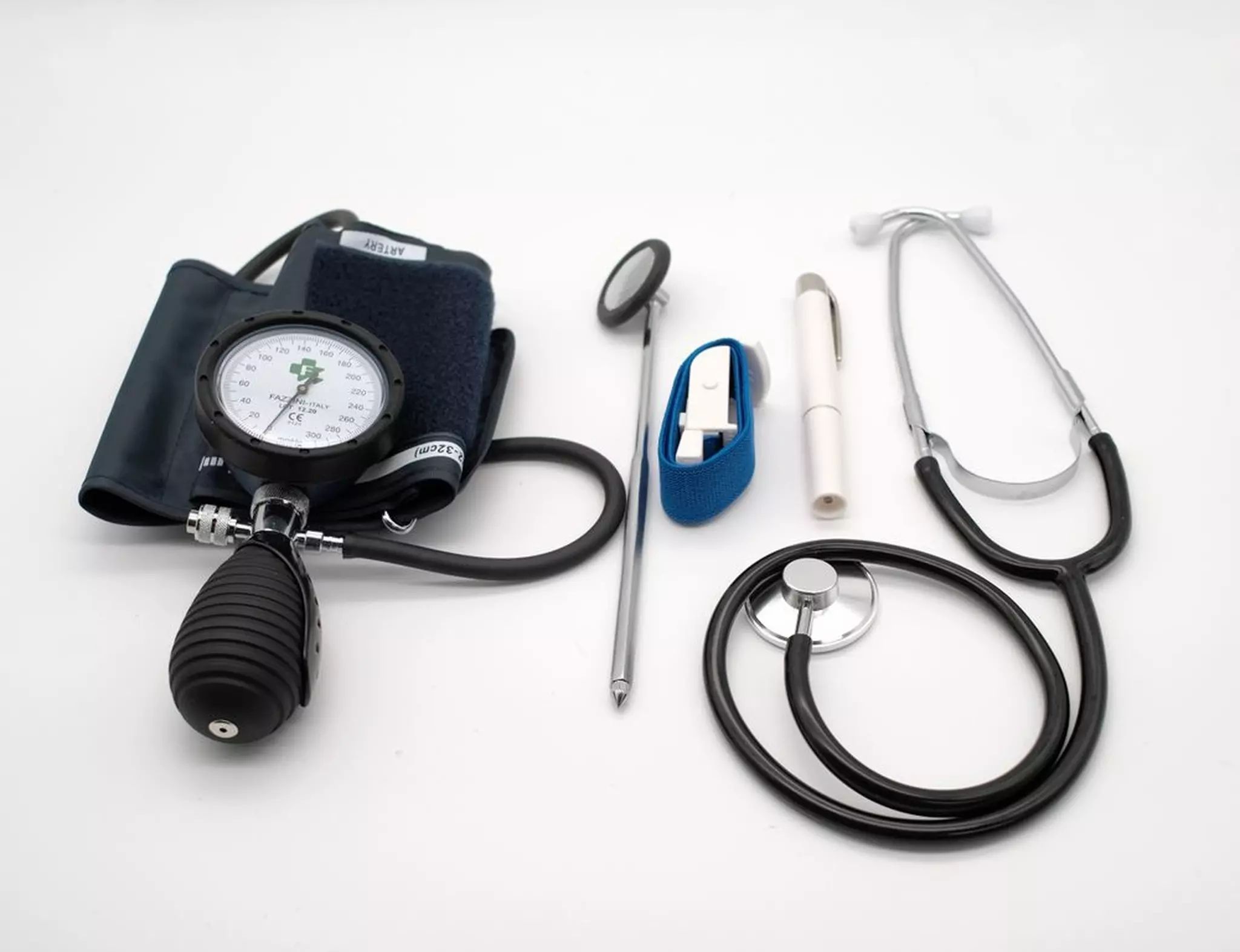Medizinisches Set mit Stethoskop, Reflexhammer, Pupillenleuchte und Blutdruckmessgerät. Auf weißem Grund.
