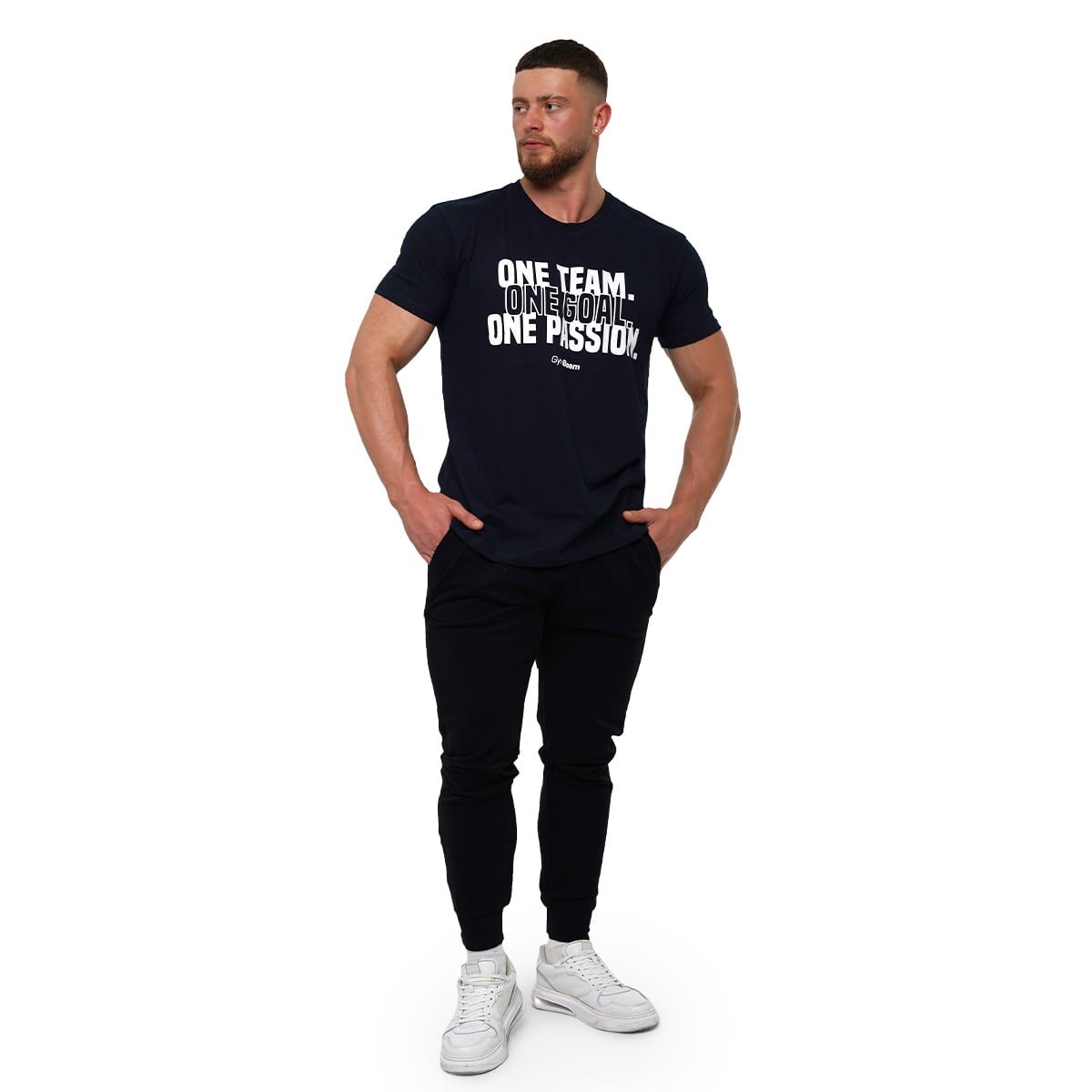 Mann in dunkelblauem T-Shirt mit weißem Aufdruck und GymBeam-Logo, steht mit Händen in den Taschen.
