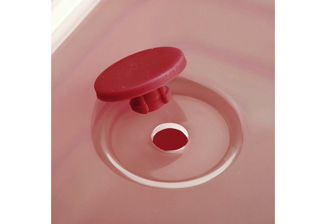 Nahaufnahme eines roten Knopfes und einer Öffnung in einer roten Frischhaltedose mit transparentem Deckel.