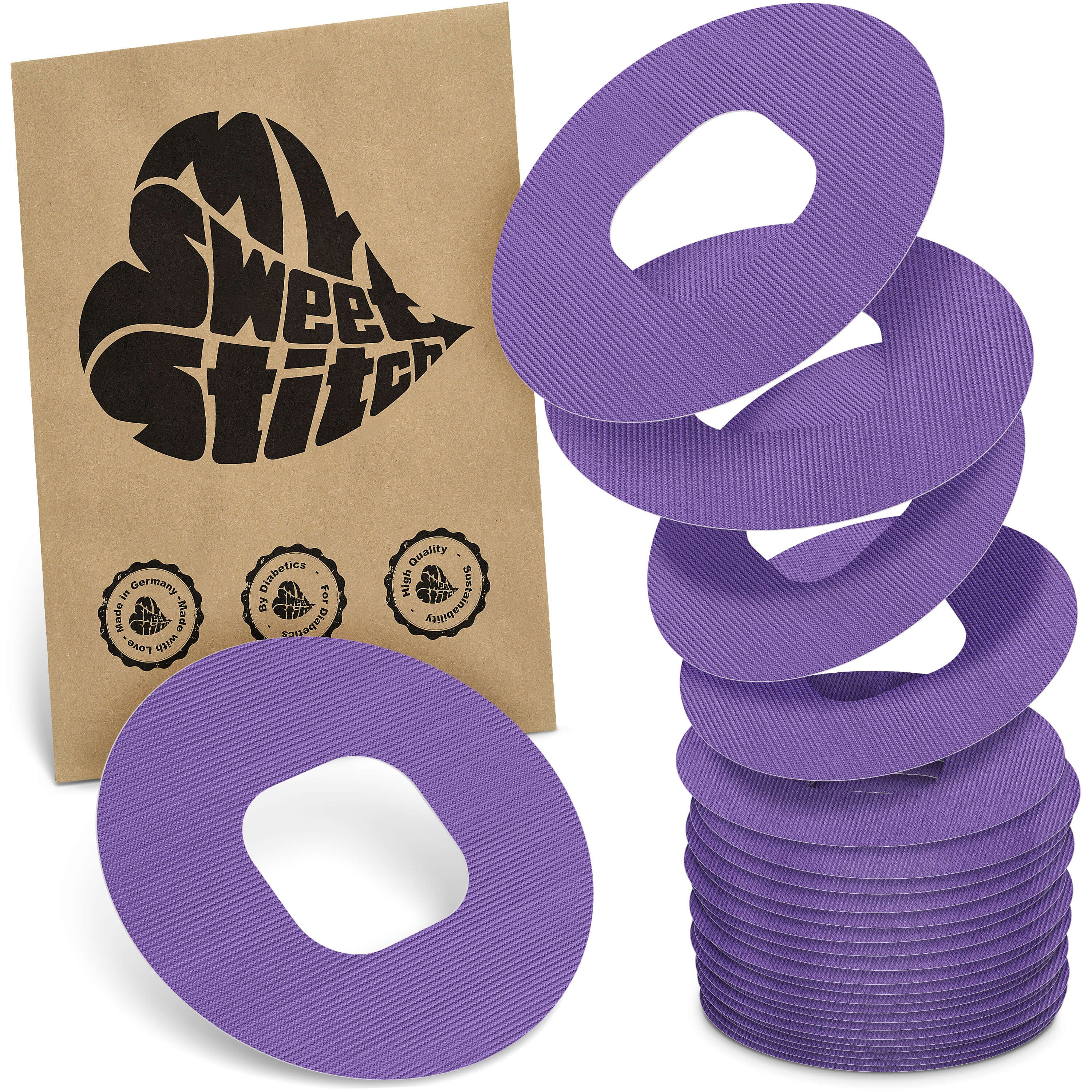 Violette, ringförmige Pflaster mit einem Loch in der Mitte. Neben einer braunen Verpackung mit Logo.