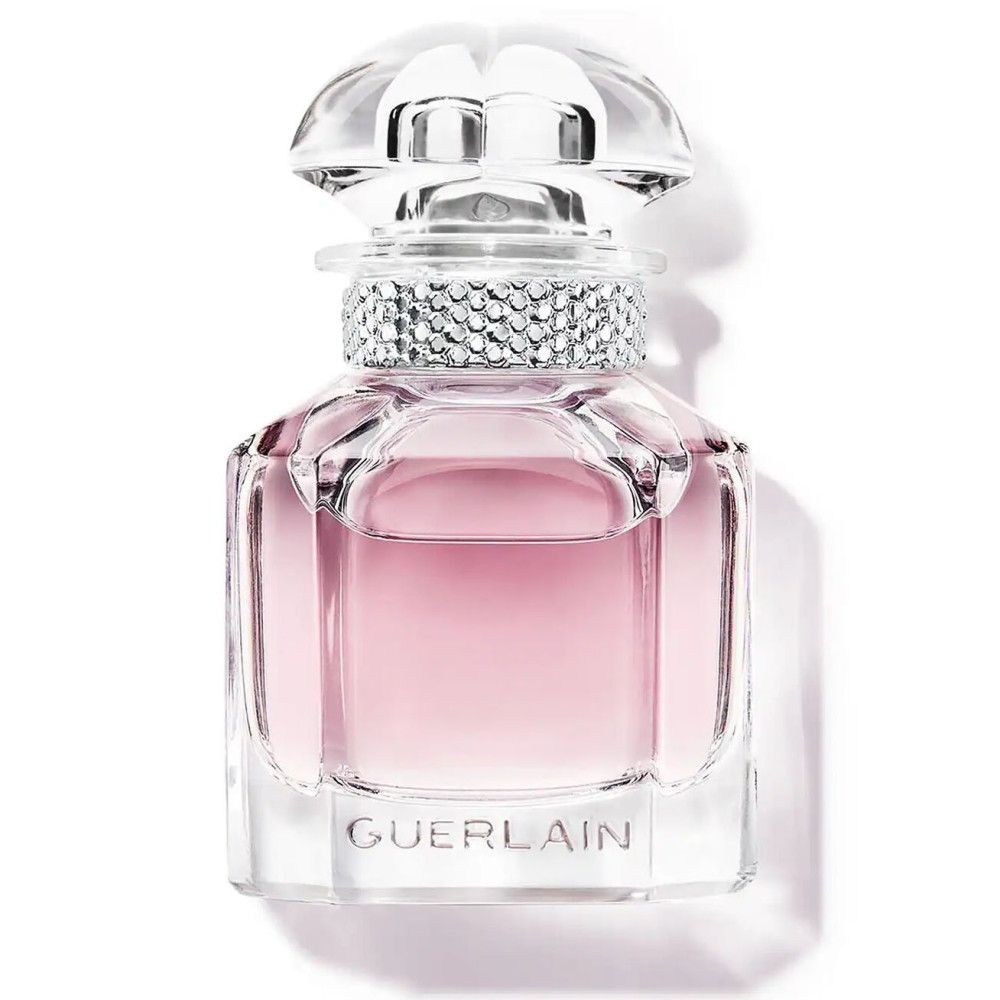 Parfümflakon mit rosa Flüssigkeit. Klarer Glasflakon mit Kristallbesatz und Deckel. Marke Guerlain unten.