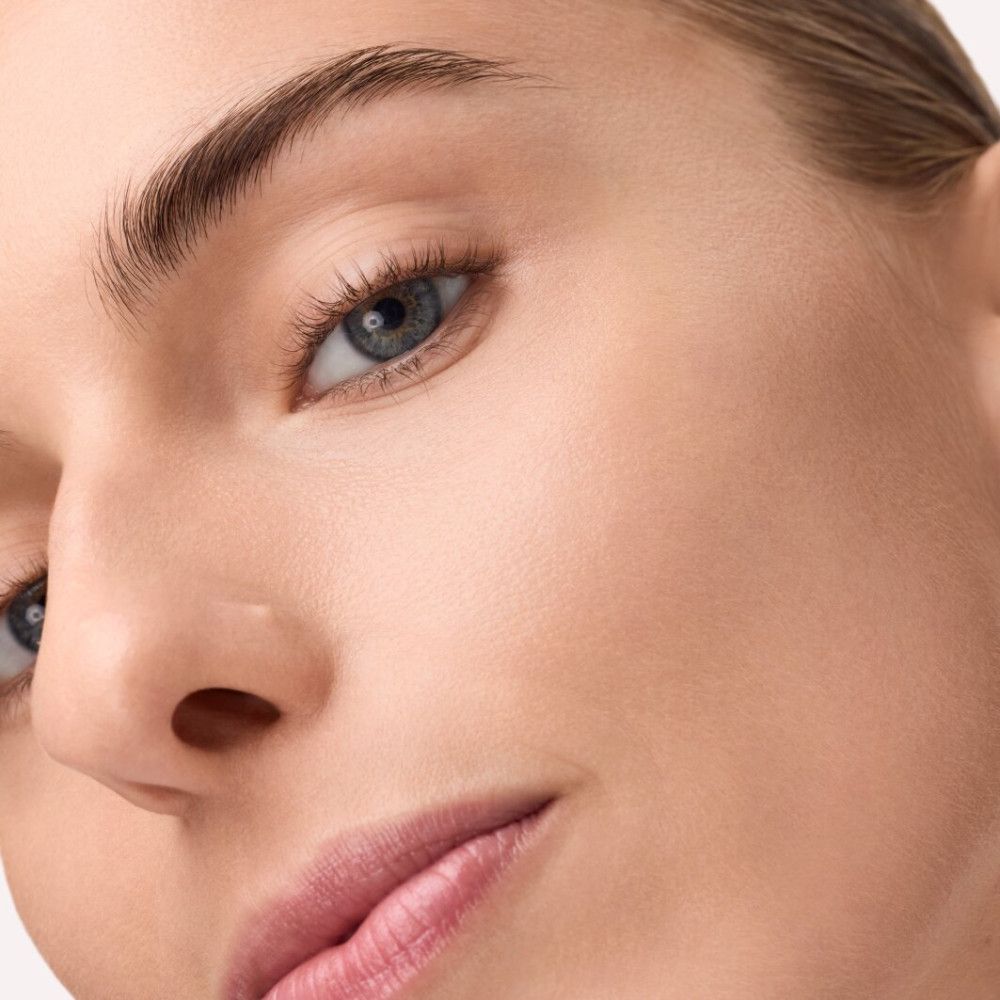 Nahaufnahme eines Gesichts. Haut wirkt ebenmäßig und gepflegt. Blaue Augen, volle Lippen.