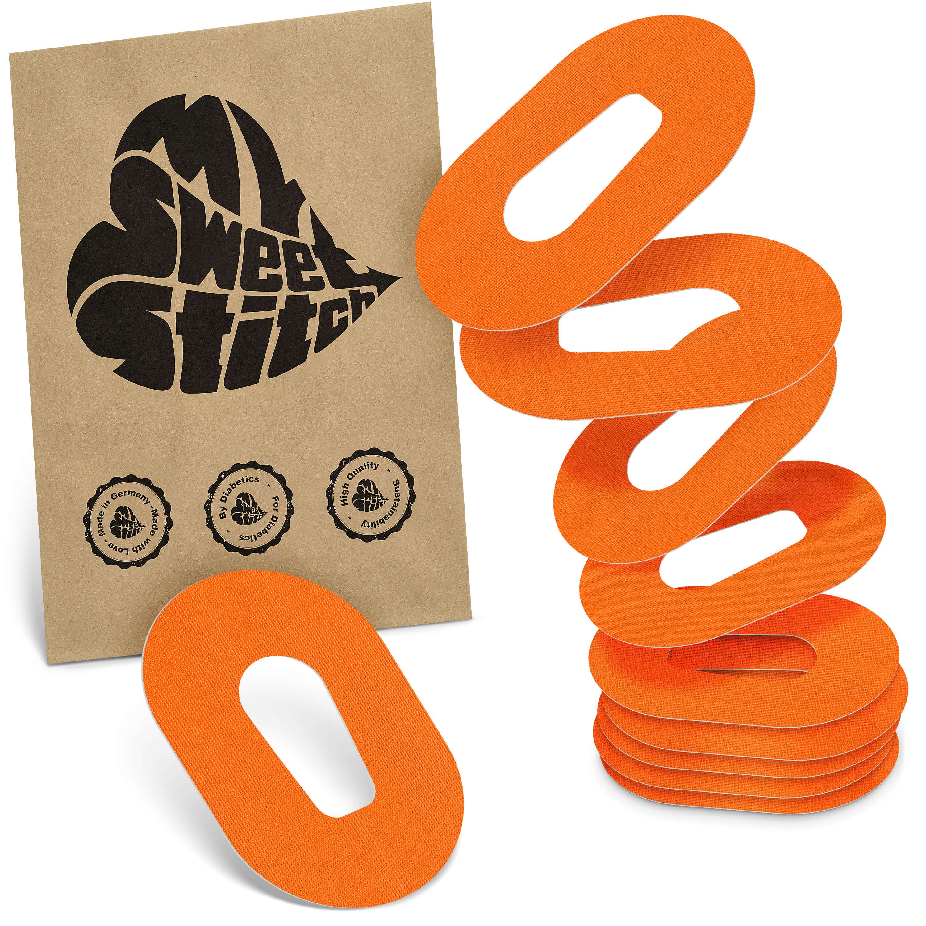 Orange, ovale Pflaster mit Loch in der Mitte, neben einer braunen Papiertüte mit schwarzem Herz-Logo.