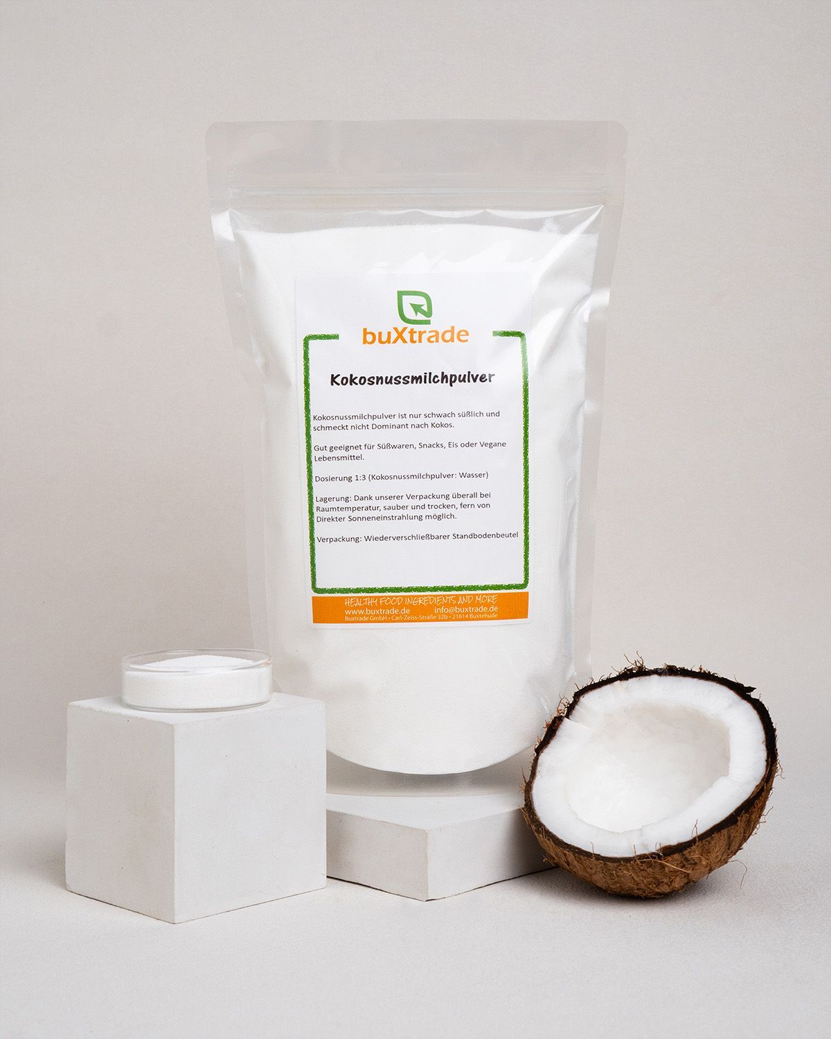 Beutel 'buXtrade Kokosnussmilchpulver', halbe Kokosnuss, Schale mit Pulver. Auf Podesten.