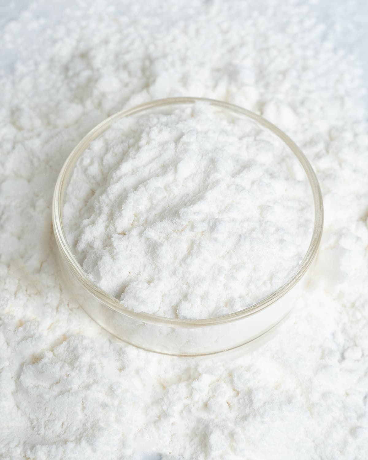 Close-up of L-Histidine Base Pulver in a small dish, surrounded by powder.