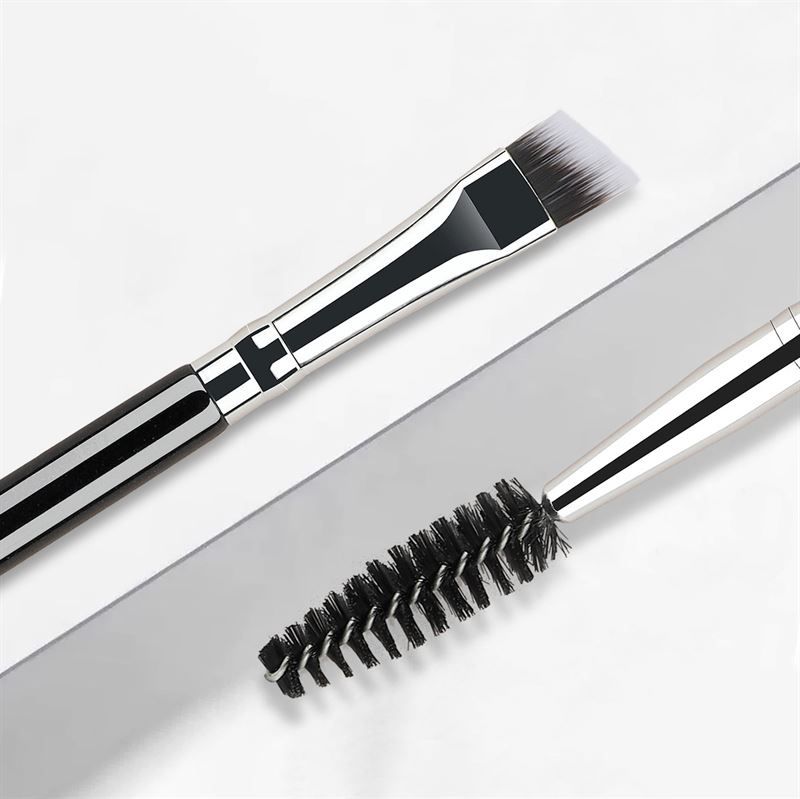 Doppel-Augenbrauenbürste. Ein Ende mit abgewinkeltem Pinsel, das andere mit spiralförmigen Borsten. Schwarze und silberne Elemente.