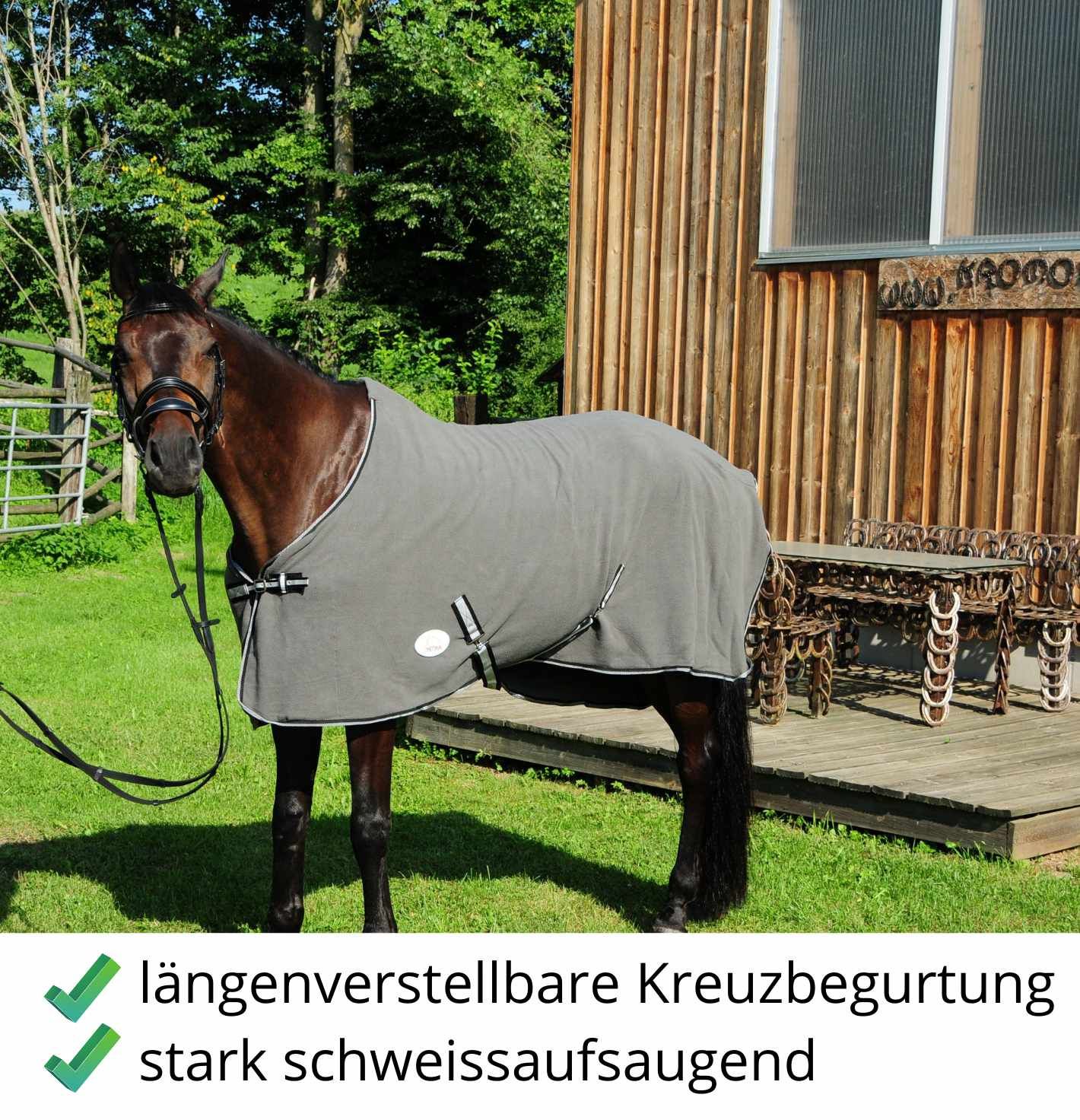 Graue Fleecedecke auf einem Pferd. Text: längenverstellbare Kreuzbegurtung, stark schweißaufsaugend.