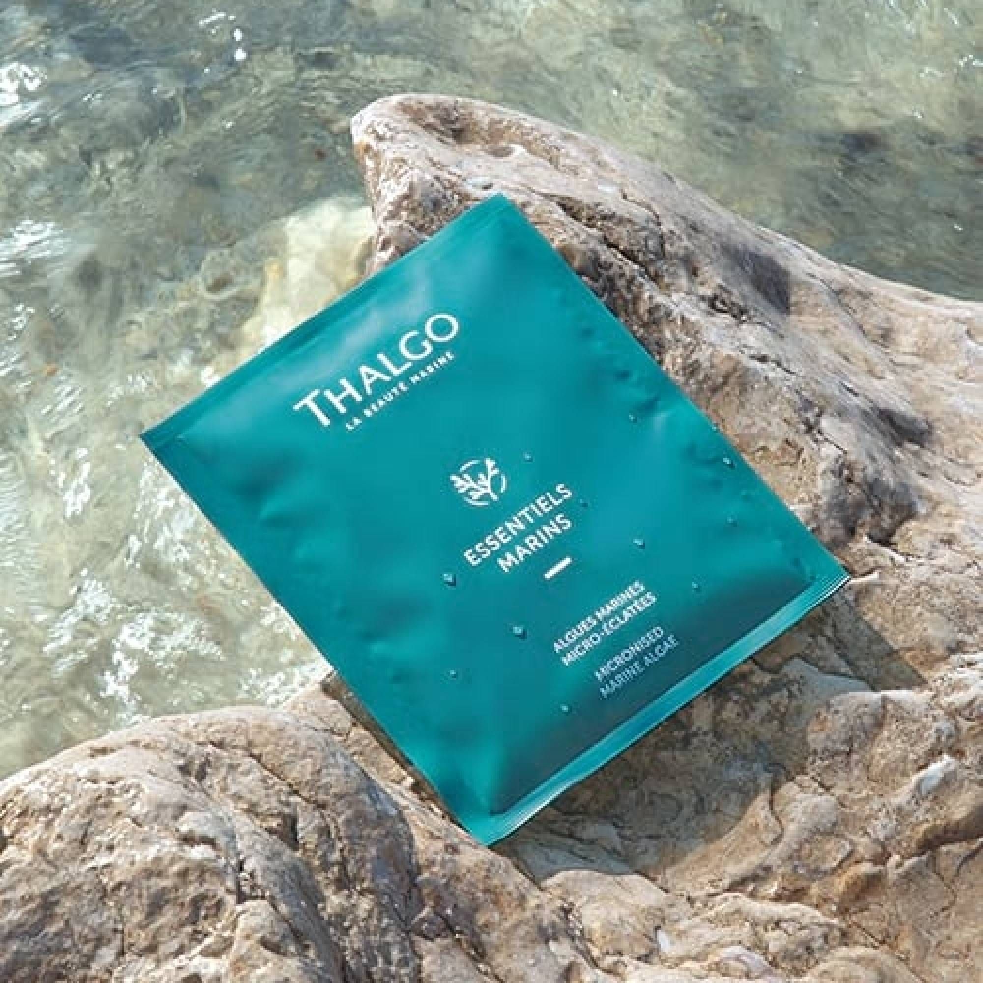 Türkisfarbene Einzelverpackung mit weißem Schriftzug THALGO. Auf einem Stein am Wasser platziert.