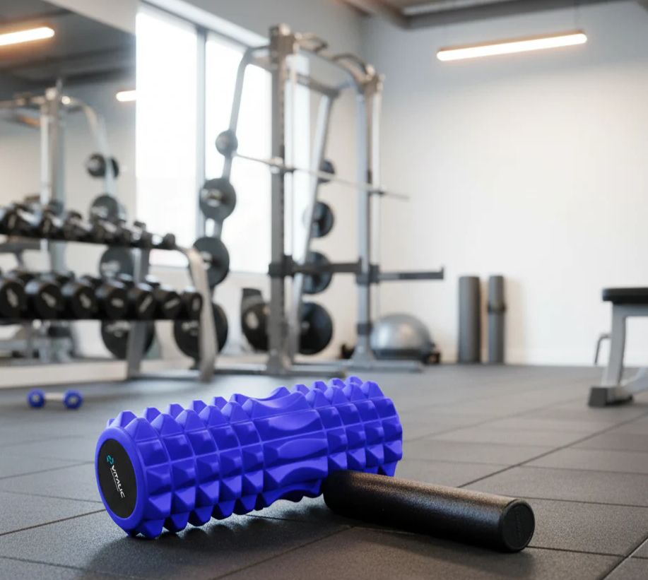 Blaue Faszienrolle und schwarze Massage-Rolle liegen auf dem Boden in einem Fitnessstudio.