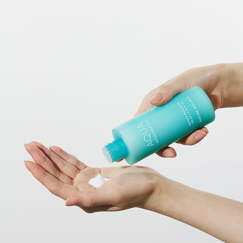 Hände halten eine türkisfarbene Flasche. Produkt wird in die Handfläche gegossen. Produktname: AQUA Super Aqua Max Watery Emulsion.