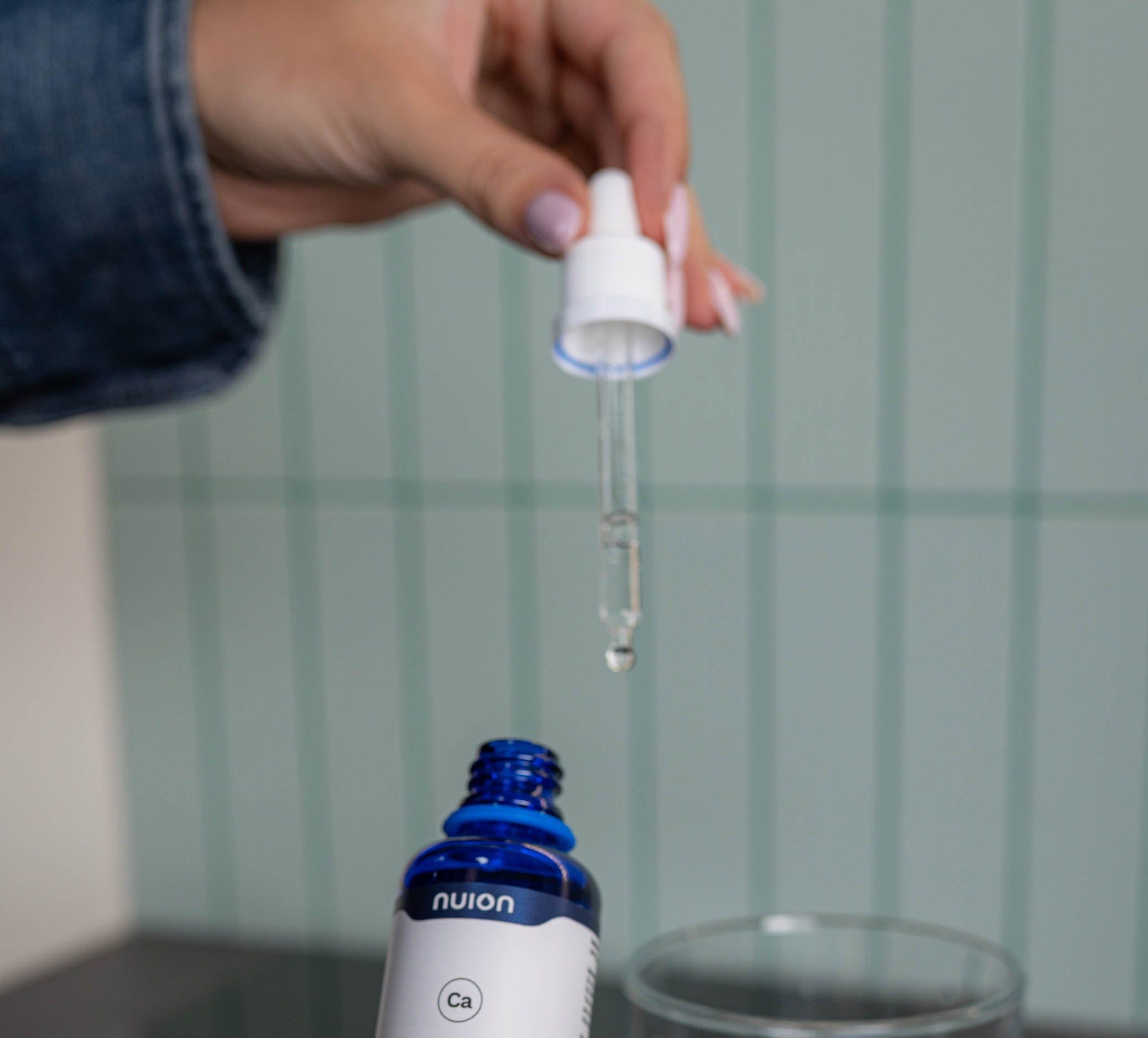 Blaue Tropfflasche mit weißem Tropfer, Etikett mit 'nuion CALCIUM'.