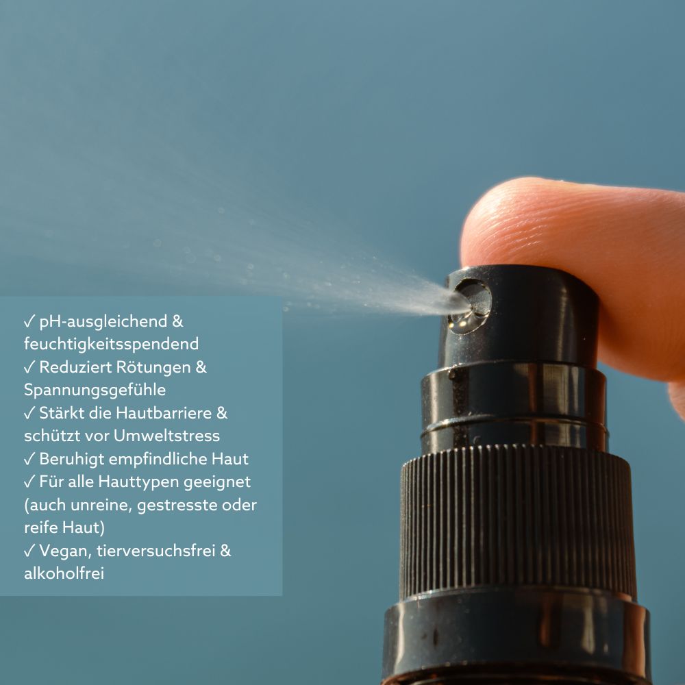 Nahaufnahme einer schwarzen Sprühflasche, die Flüssigkeit versprüht. Text: pH-ausgleichend, feuchtigkeitsspendend, reduziert Rötungen, vegan.