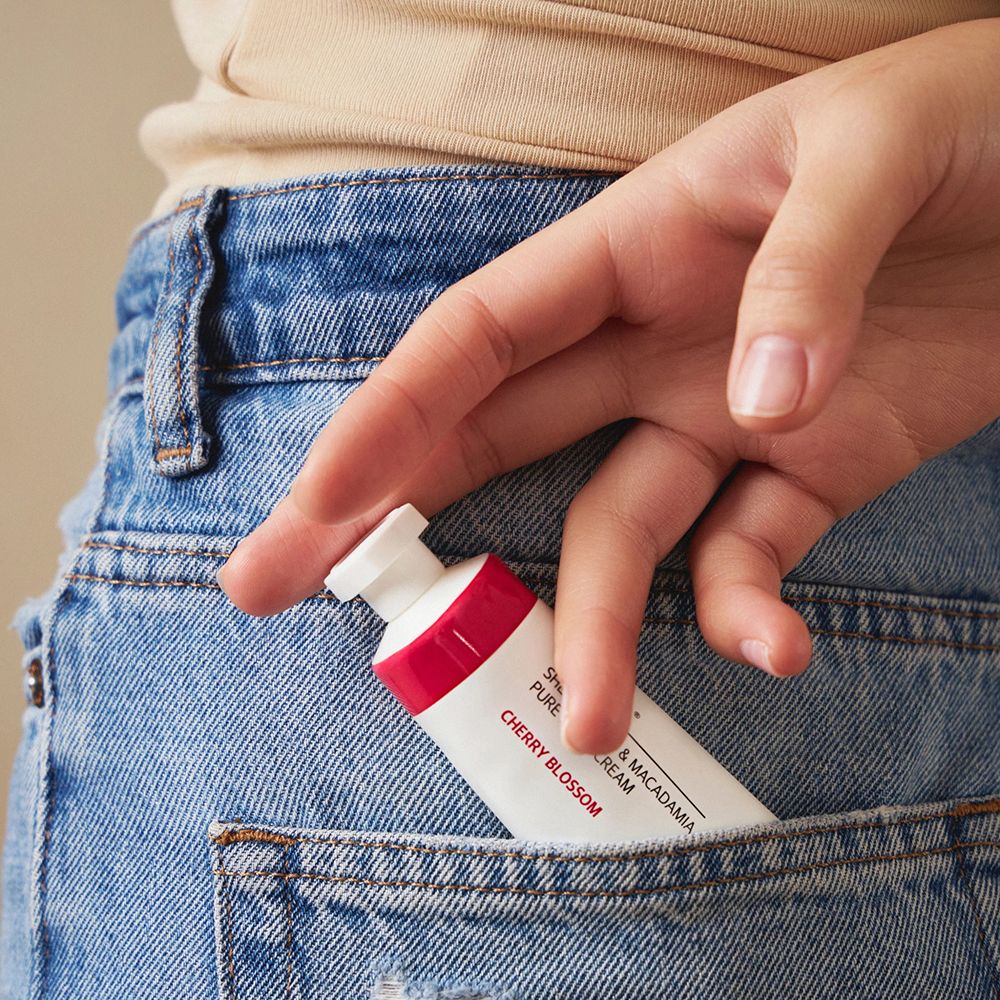 Handcreme-Tube in Jeans-Hosentasche. Auf der Tube steht: KUNDAL Handcreme Cherry Blossom mit Sheabutter & Macadamia.