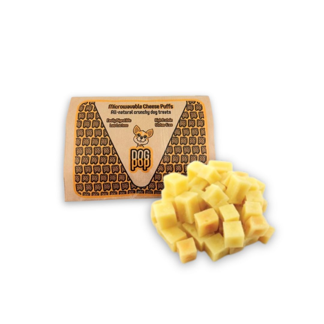 Karton mit Käsewürfeln. Aufschrift: Microwaveable Cheese Puffs, All-natural crunchy dog treats. Käsewürfel daneben.