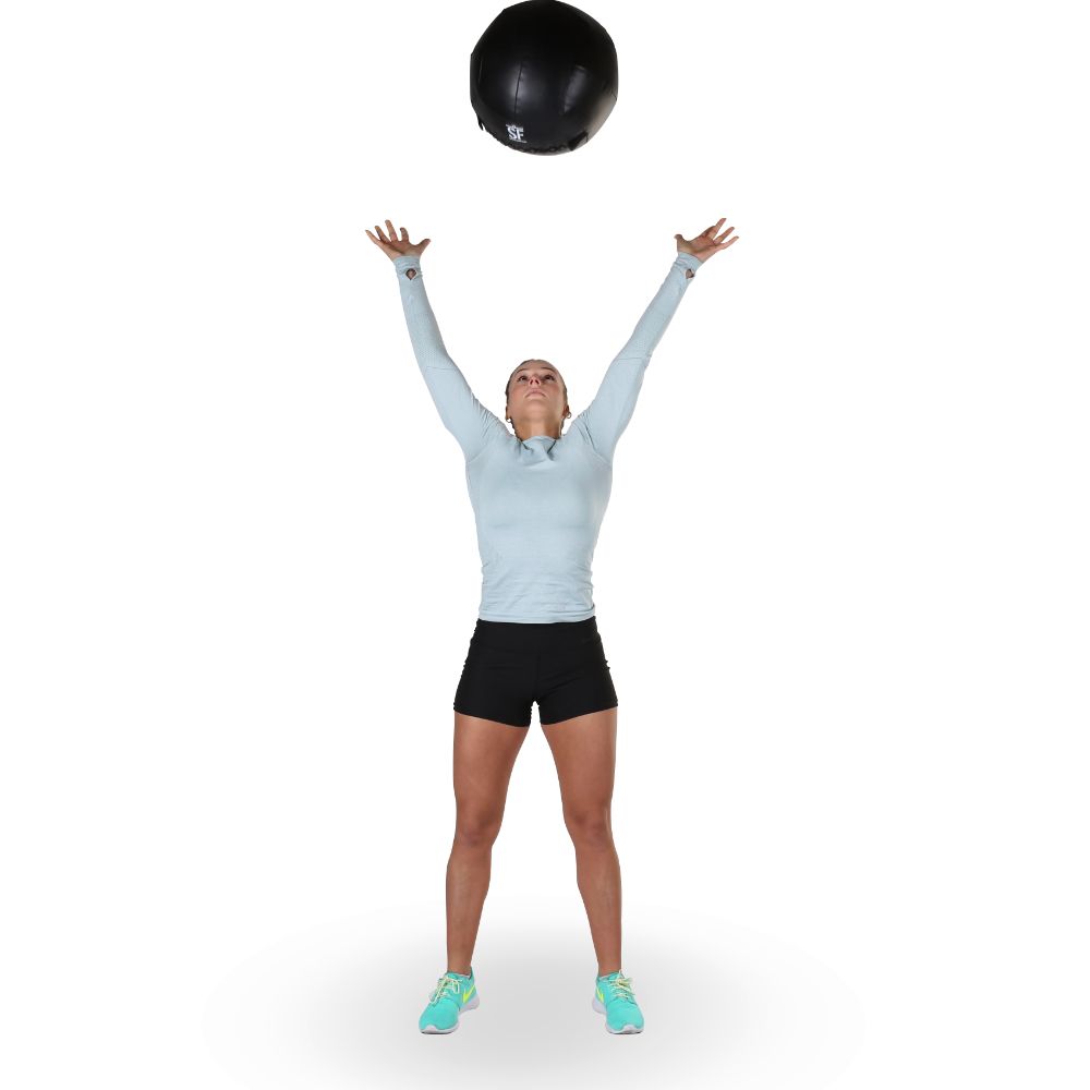 Frau wirft einen schwarzen Medizinball in die Luft. Sportkleidung.