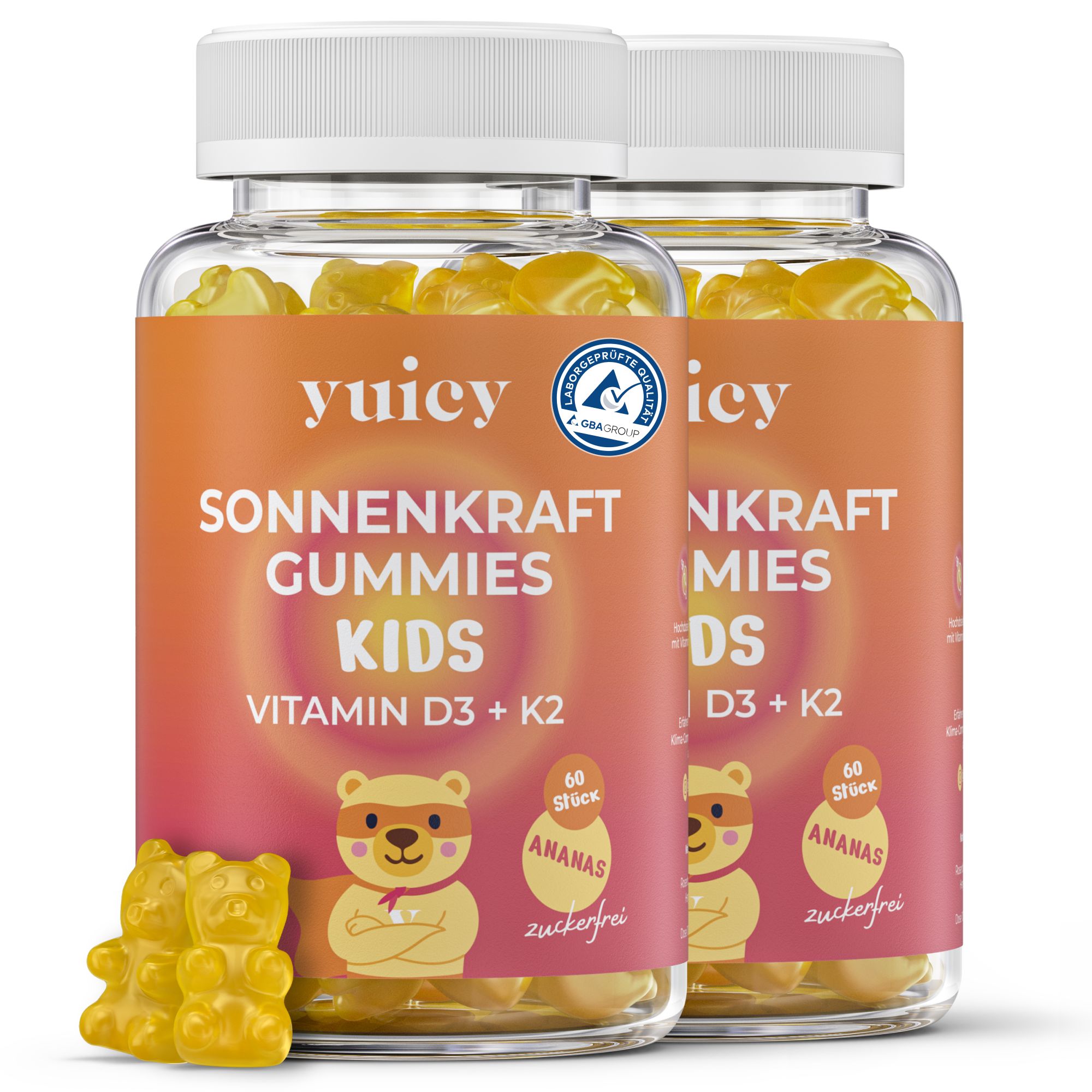 Zwei Flaschen mit gelben Gummibärchen. Aufschrift: yuicy Sonnenkraft Gummies Kids Vitamin D3 + K2. Zwei Gummibärchen liegen davor.