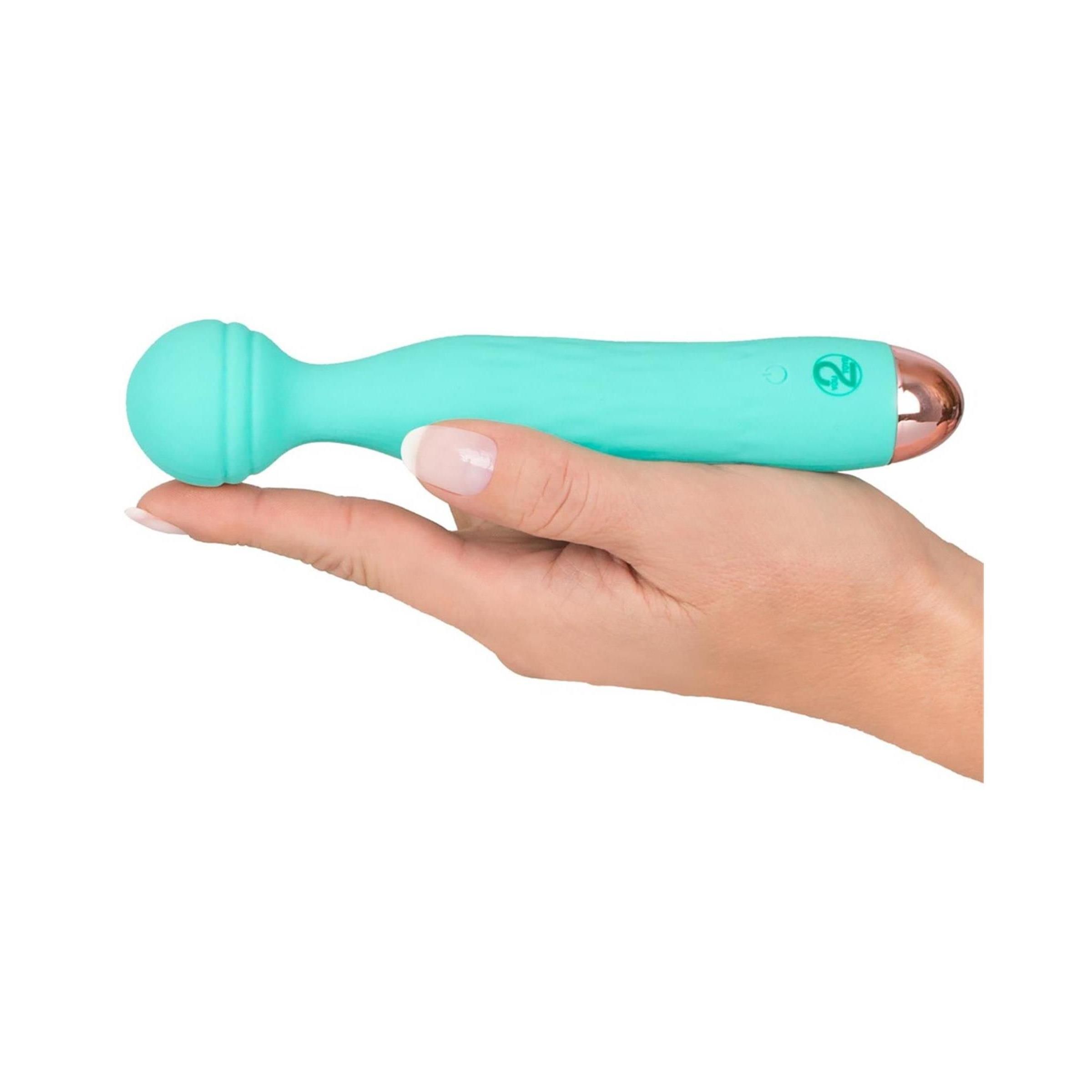 Türkisgrüner Vibrator mit abgerundetem Kopf und goldfarbener Spitze. Gehalten in einer Hand.
