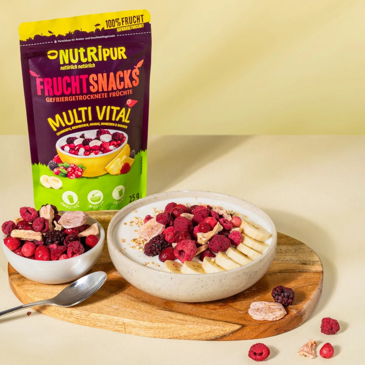 Schale mit Joghurt und gefriergetrockneten Früchten. Daneben eine Tüte NutriPur Frucht Snacks. Auf einem Holzbrett.