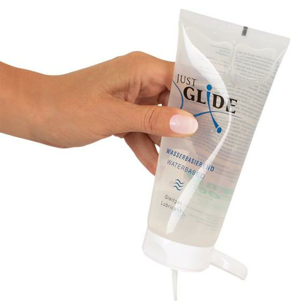 Hand hält Tube. Produkt wird herausgedrückt. Aufschrift: JUST GLIDE, wasserbasiert.