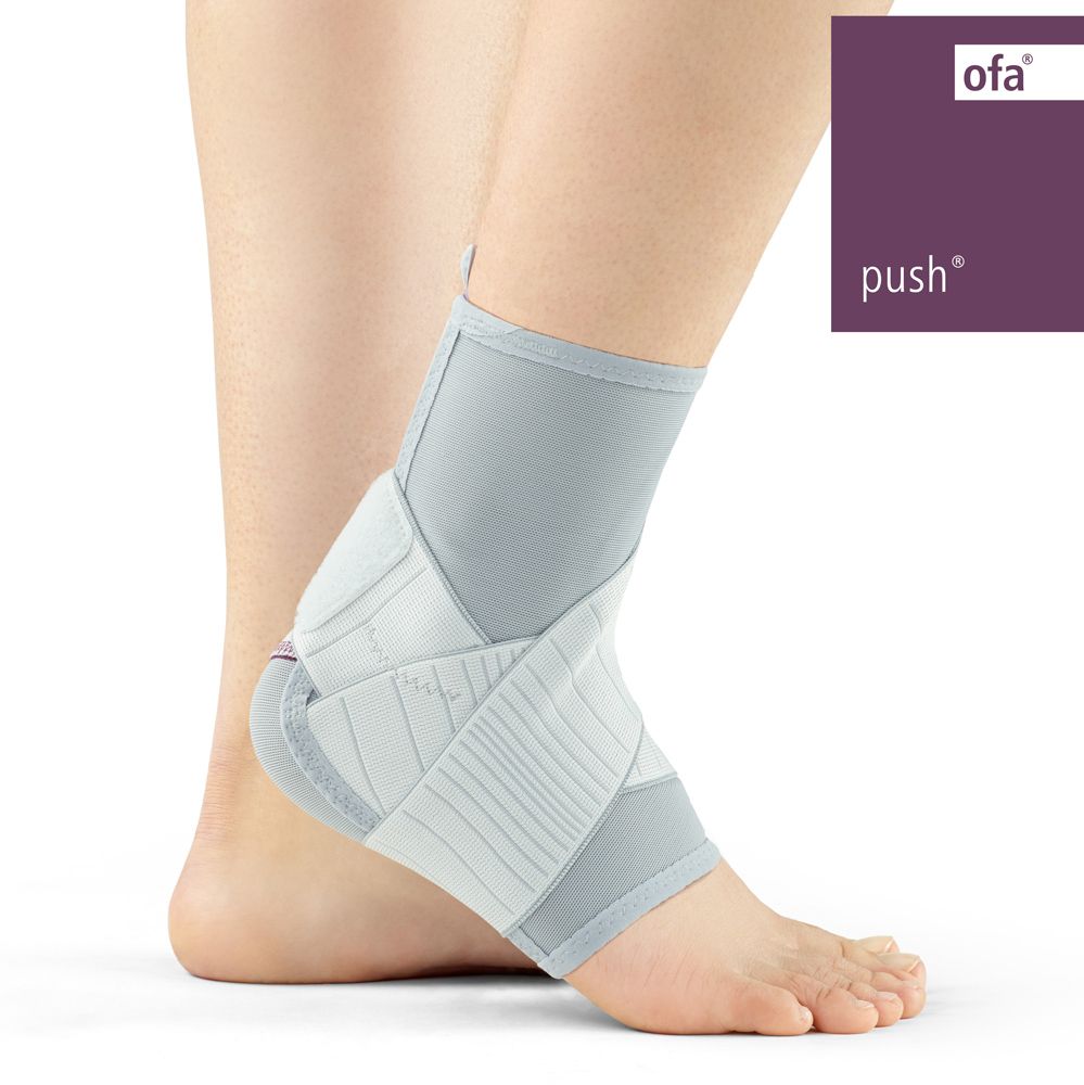 Graue Push care Knöchelbandage mit Klettverschluss, an einem Fuß getragen.