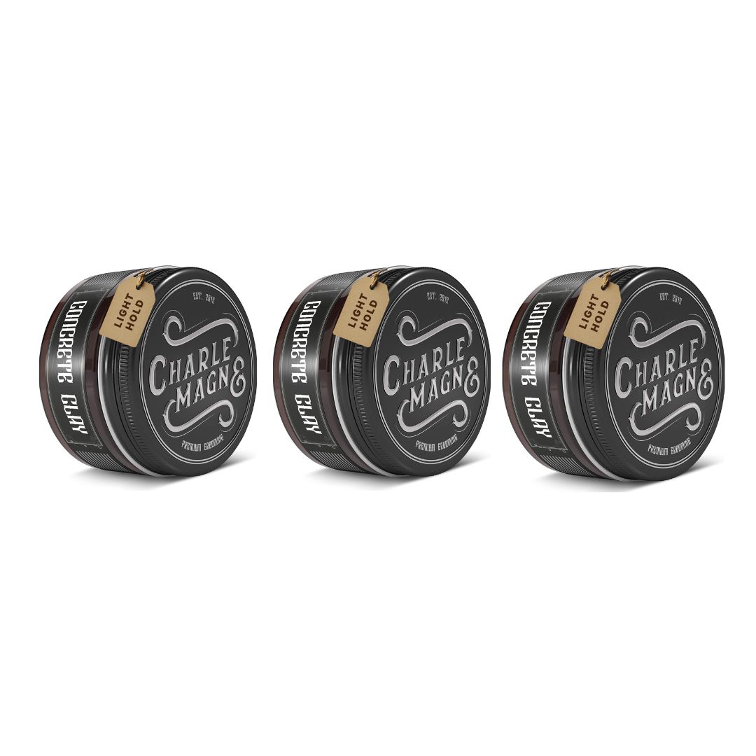 Drei runde, schwarze Dosen mit Deckel. Auf jeder Dose steht "Concrete Clay" und "CHARLE MAGNE &" sowie ein Anhänger mit "LIGHT HOLD".