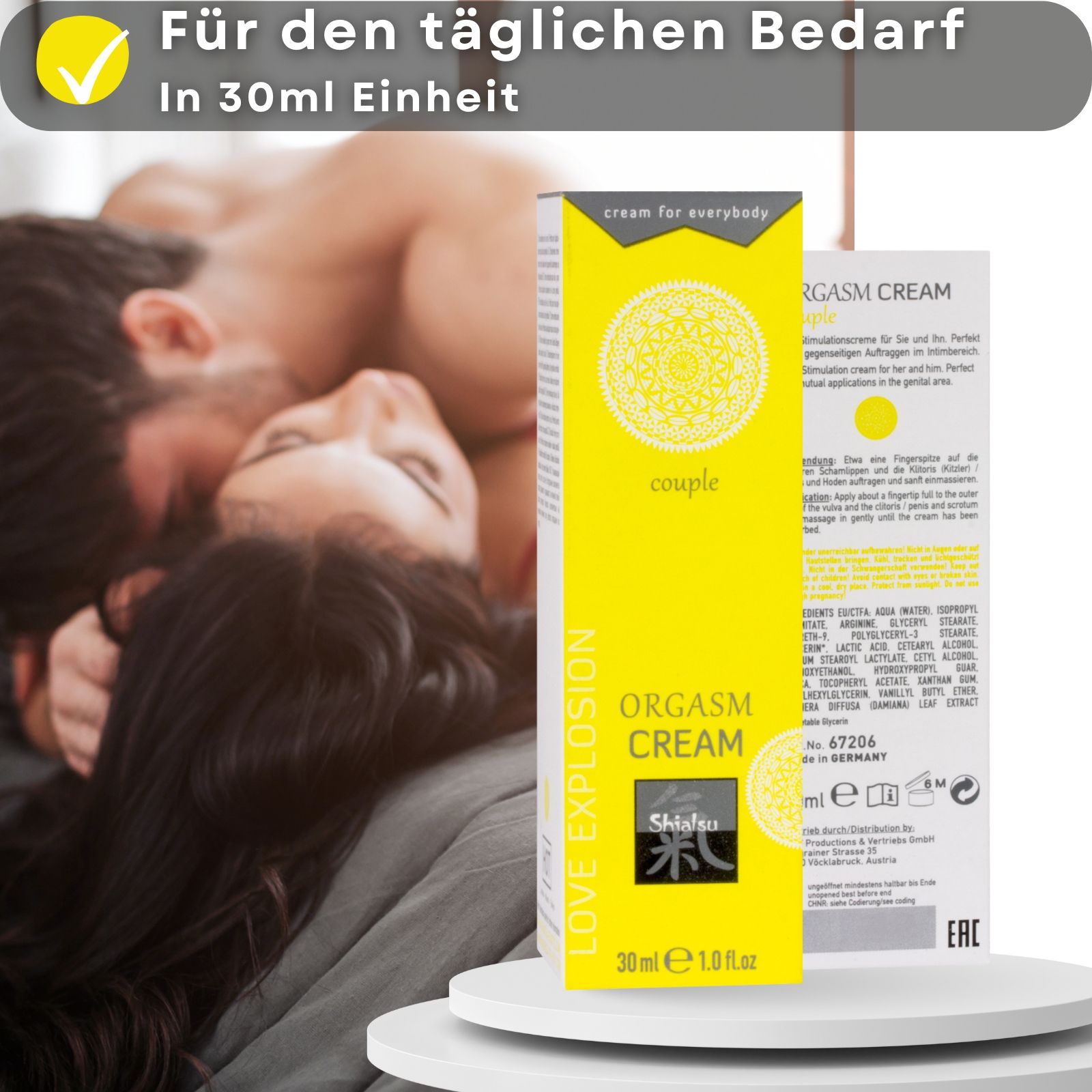Gelbe Tube und Schachtel. Aufschrift: ORGASM CREAM, Shiatsu, 30 ml. Paar im Hintergrund.