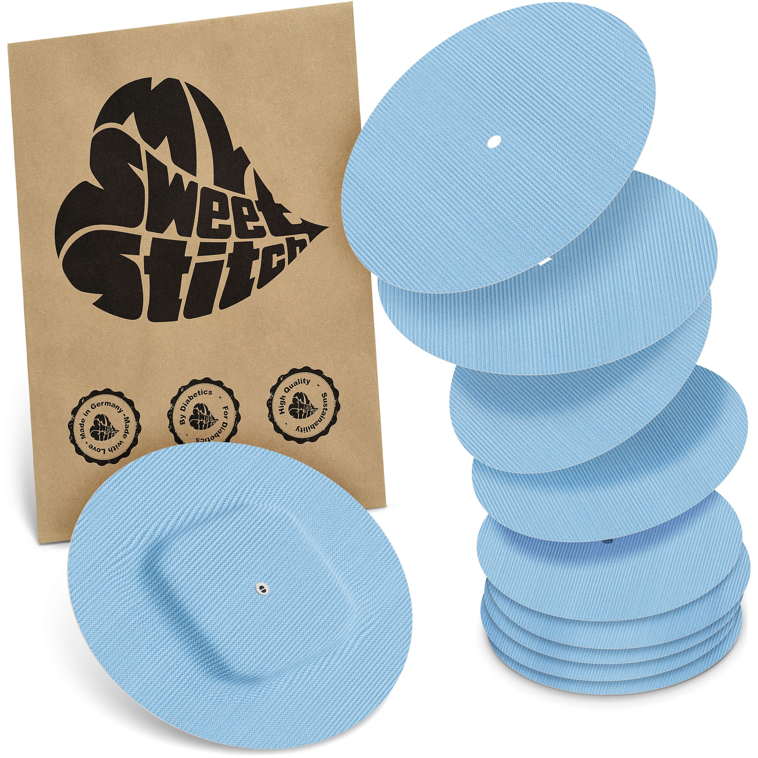 Hellblaue, runde Pflaster mit geriffelter Oberfläche. Neben einer braunen Verpackung mit Logo liegen mehrere Pflaster gestapelt.