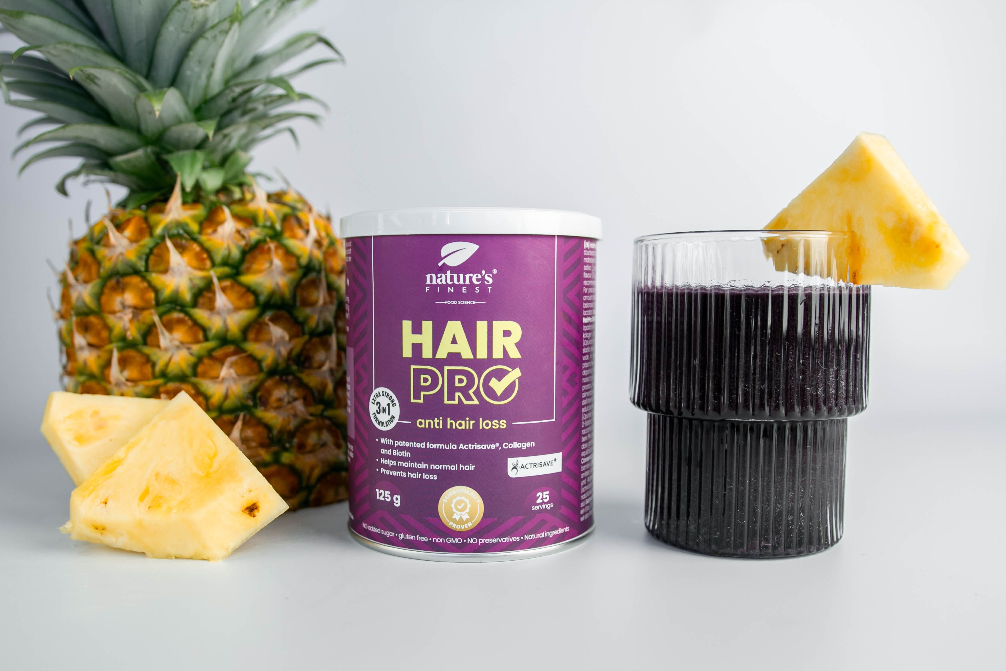 Dose Nature's Finest Hair Pro, Ananas, Glas mit Flüssigkeit und Ananasstück. Produkt mit Aufschrift 'Hair Pro' gegen Haarausfall.
