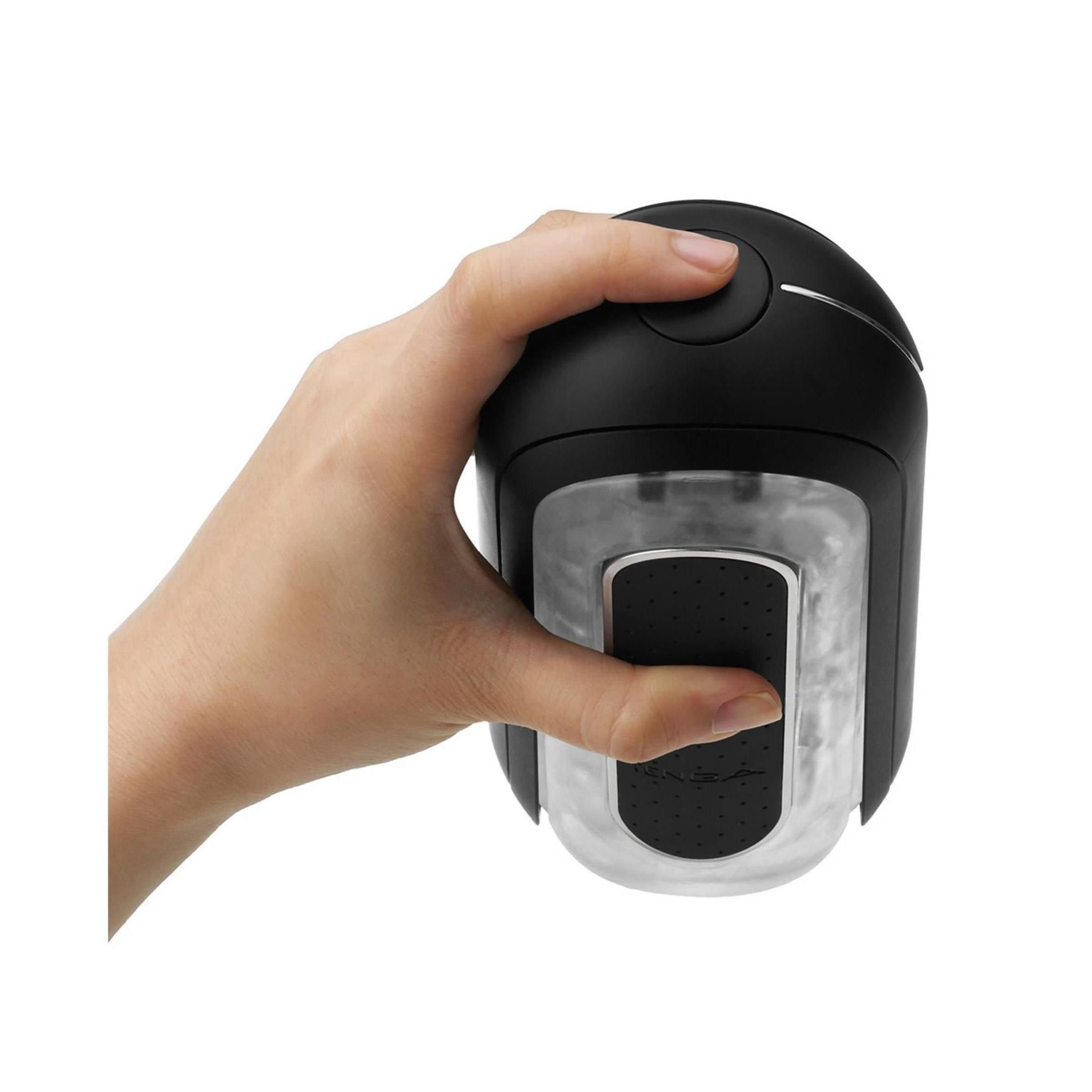 Hand hält ein schwarzes, ovales Gerät. Ein Knopf. Transparente Innenseite.