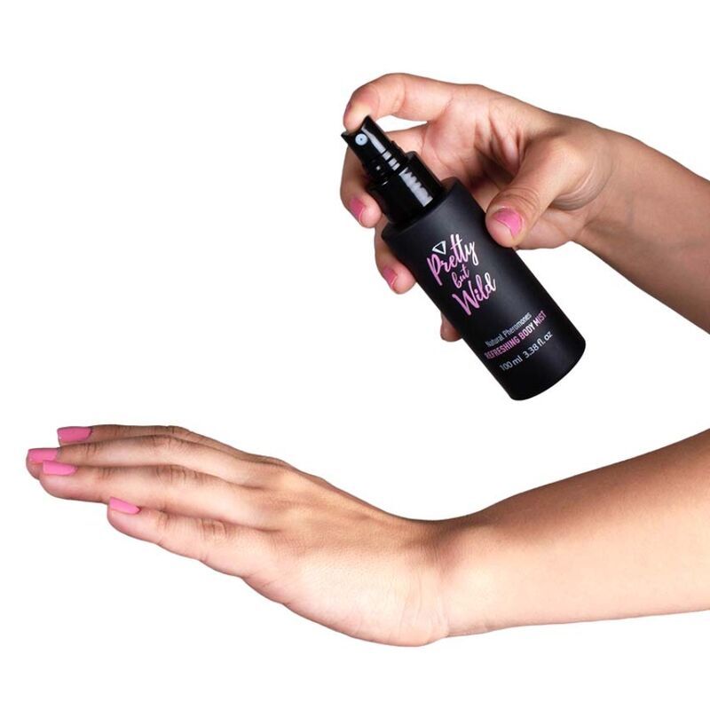 Schwarze Sprühflasche mit "Pretty but Wild"-Logo. Eine Hand sprüht auf eine andere Hand. Rosa Nagellack.